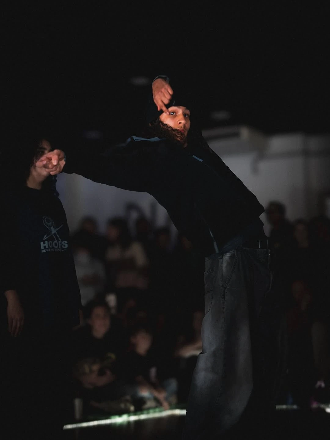 A group of dancers practicing in a mirrored studio, wearing matching outfits and engaging in synchronized movements.