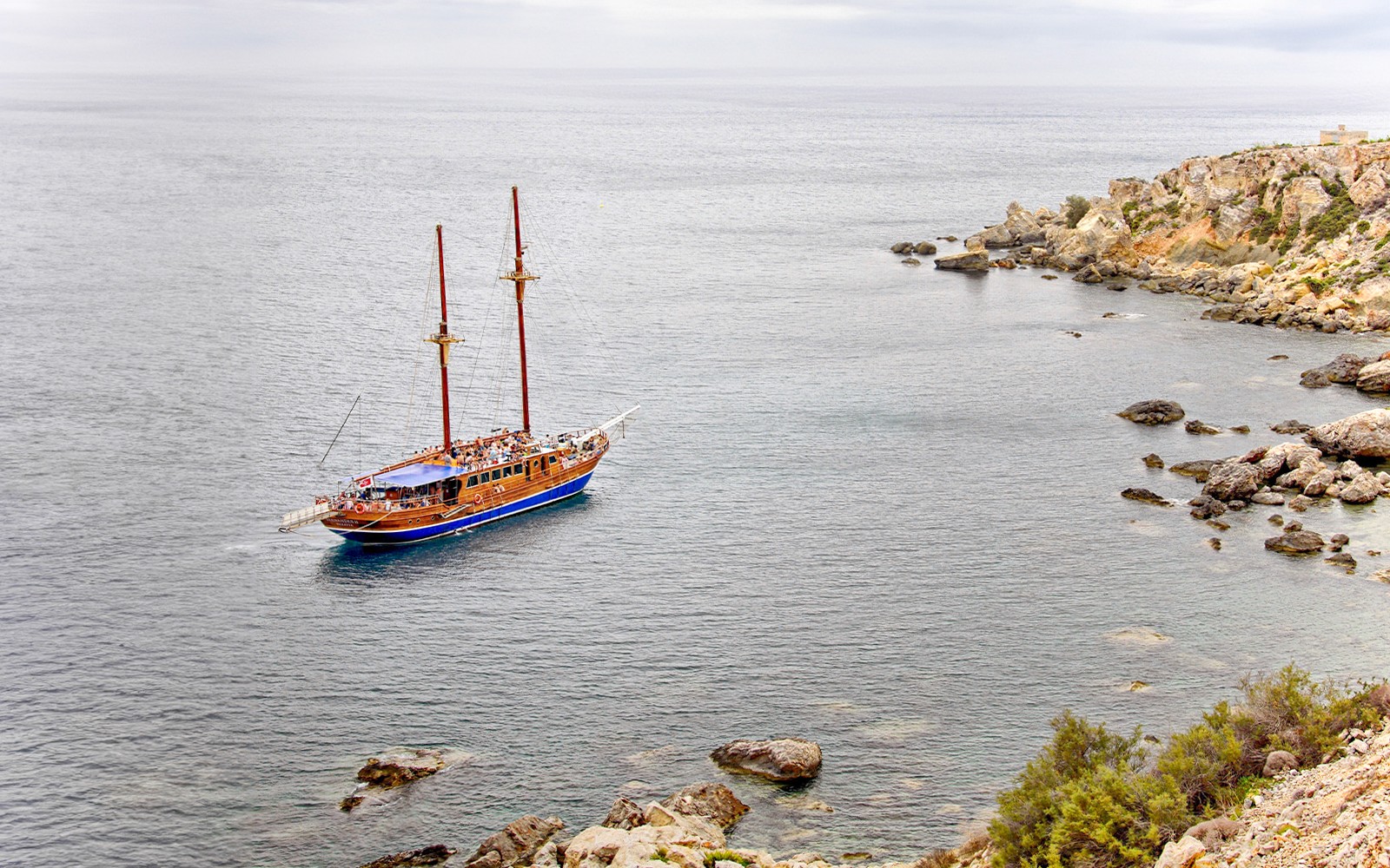 Turkish gulet sailing near rocky coast from Sliema to Gozo and Comino.