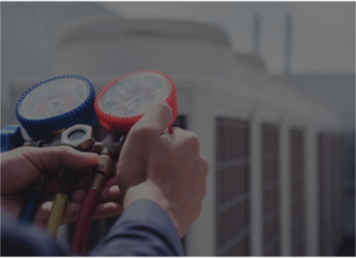 Hands of an HVAC technician using a pressure gauge to inspect and service an air conditioning unit.