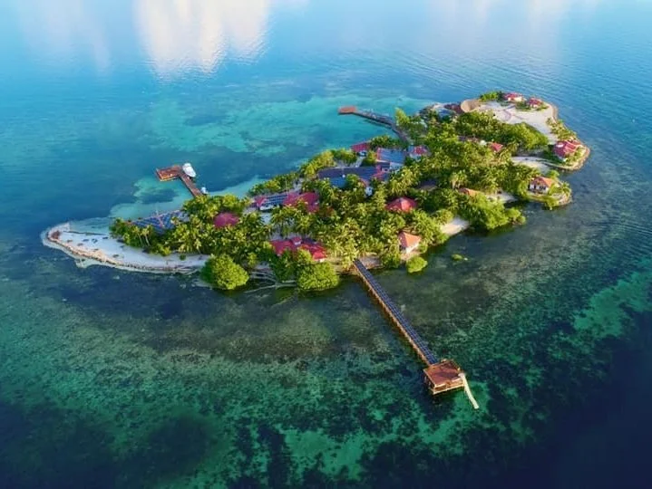 Group yoga class practicing warrior pose in a spacious studio overlooking mountains and sea views.