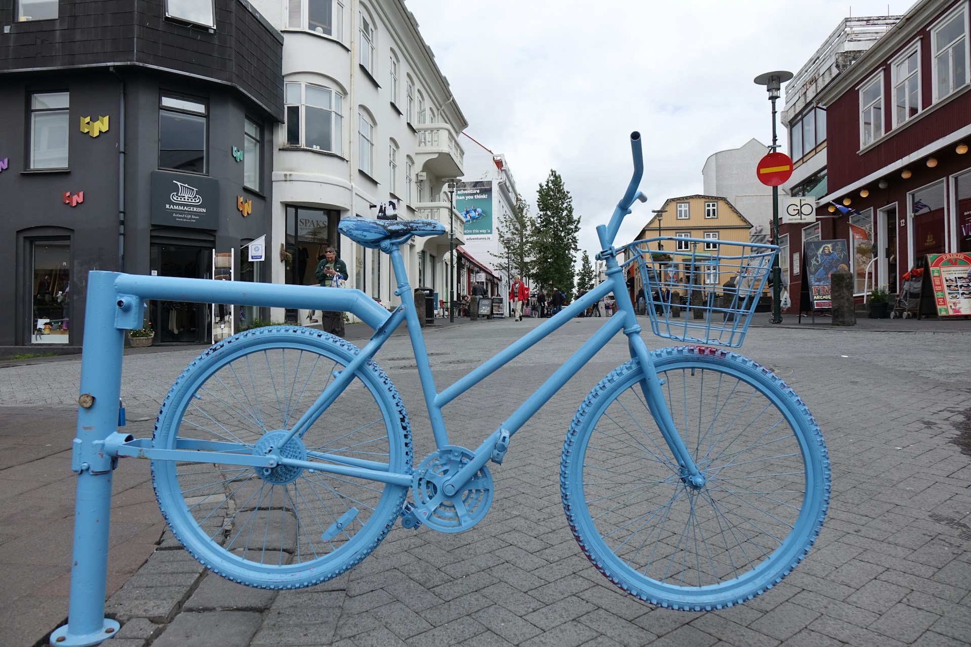 Blue bicycle installation on Laugavegur, Reykjavík's main shopping street, surrounded by shops, cafés, and colorful buildings.