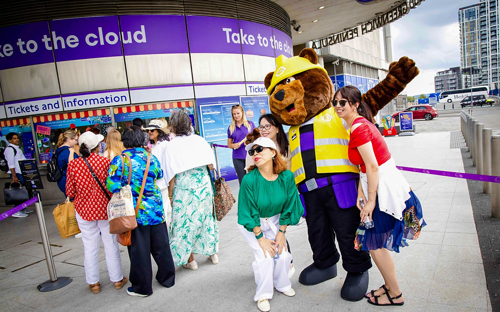 Guests posing with a mascot at IFS Cloud Cable Car entrance in London.