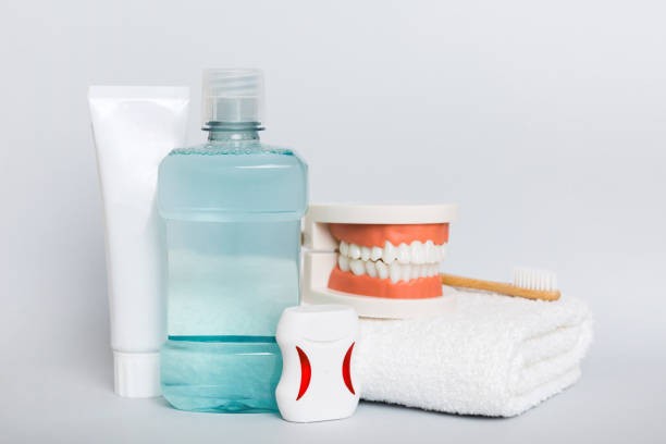 Conjunto de produtos de higiene bucal, incluindo escova de dentes, fio dental, creme dental e enxaguante, representando os cuidados essenciais para facetas de porcelana.