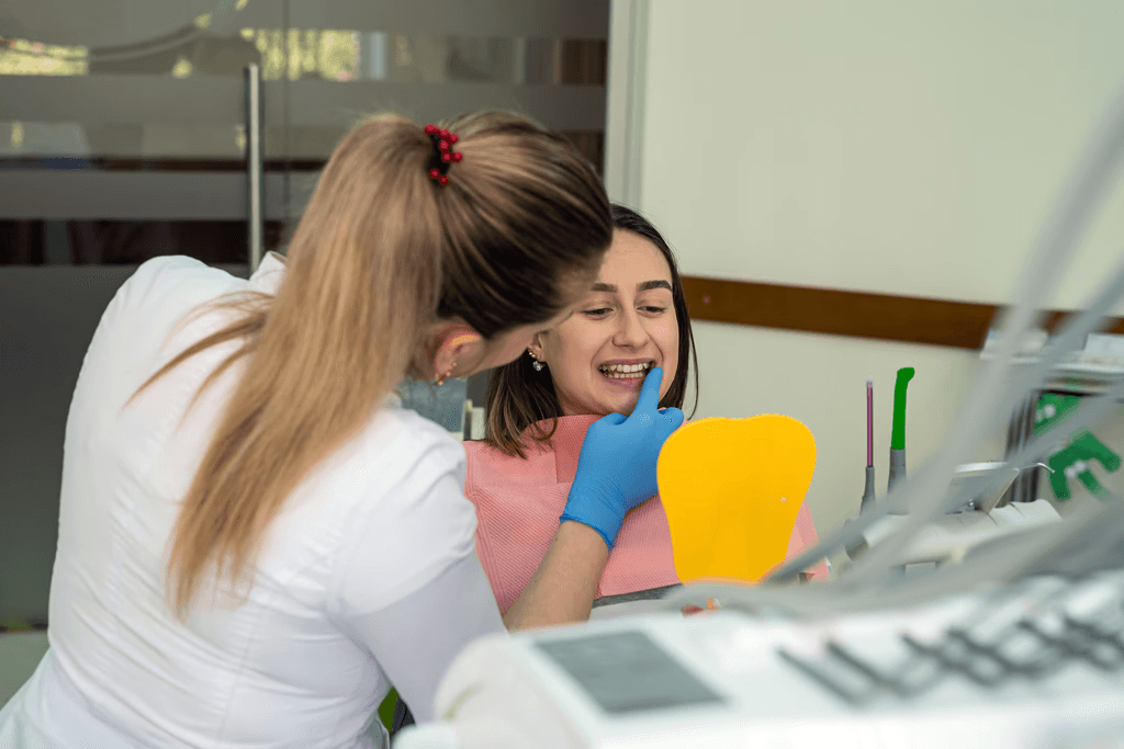 Invisalign in Dubai with a woman smiling confidently, holding her clear aligners, highlighting discreet and effective treatment.