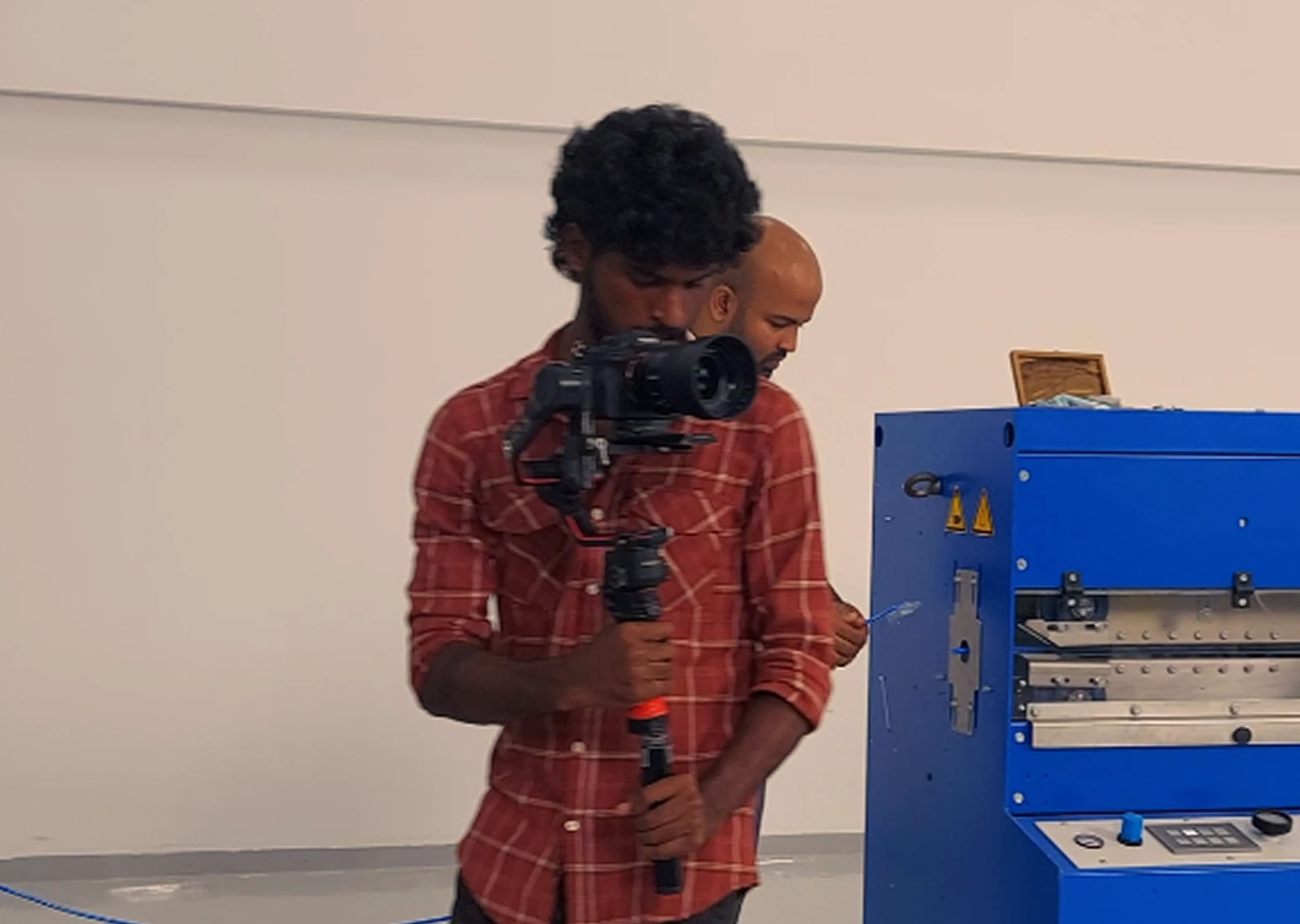 Man films video production indoors with camera and tripod during professional studio shoot