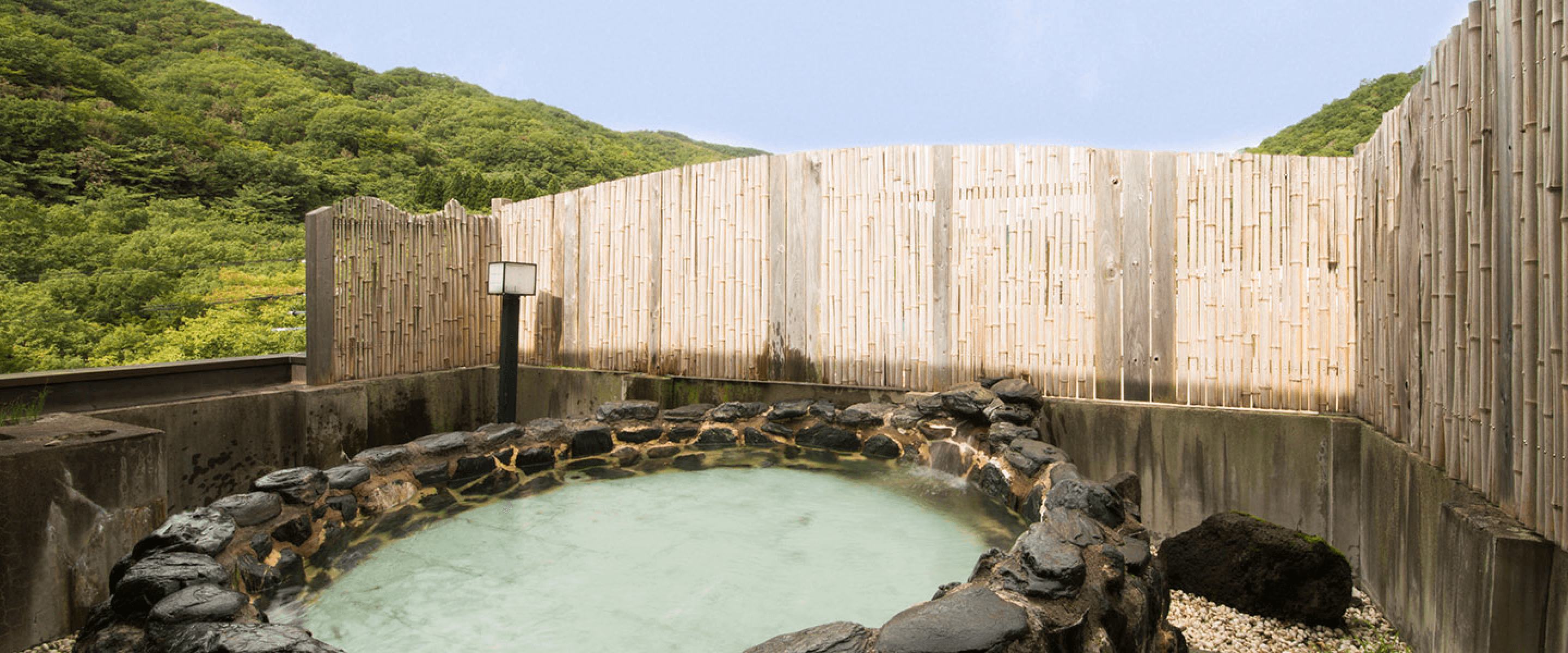 Outdoor hot spring bath with mountains in the background
