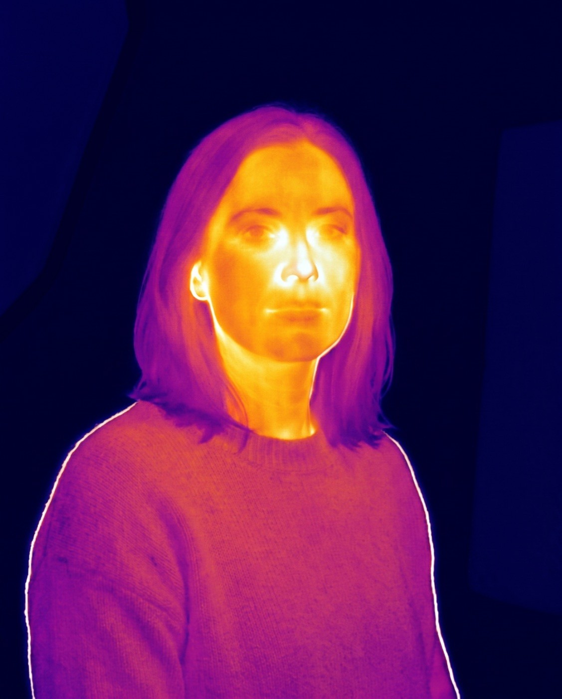 El mismo retrato como captura de cámara térmica: cara en blanco y naranja, fondo azul frío.