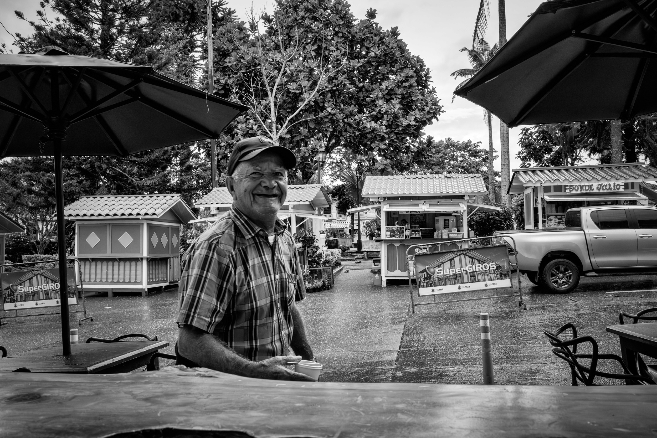 Rainy street scene with people passing by a bar window.