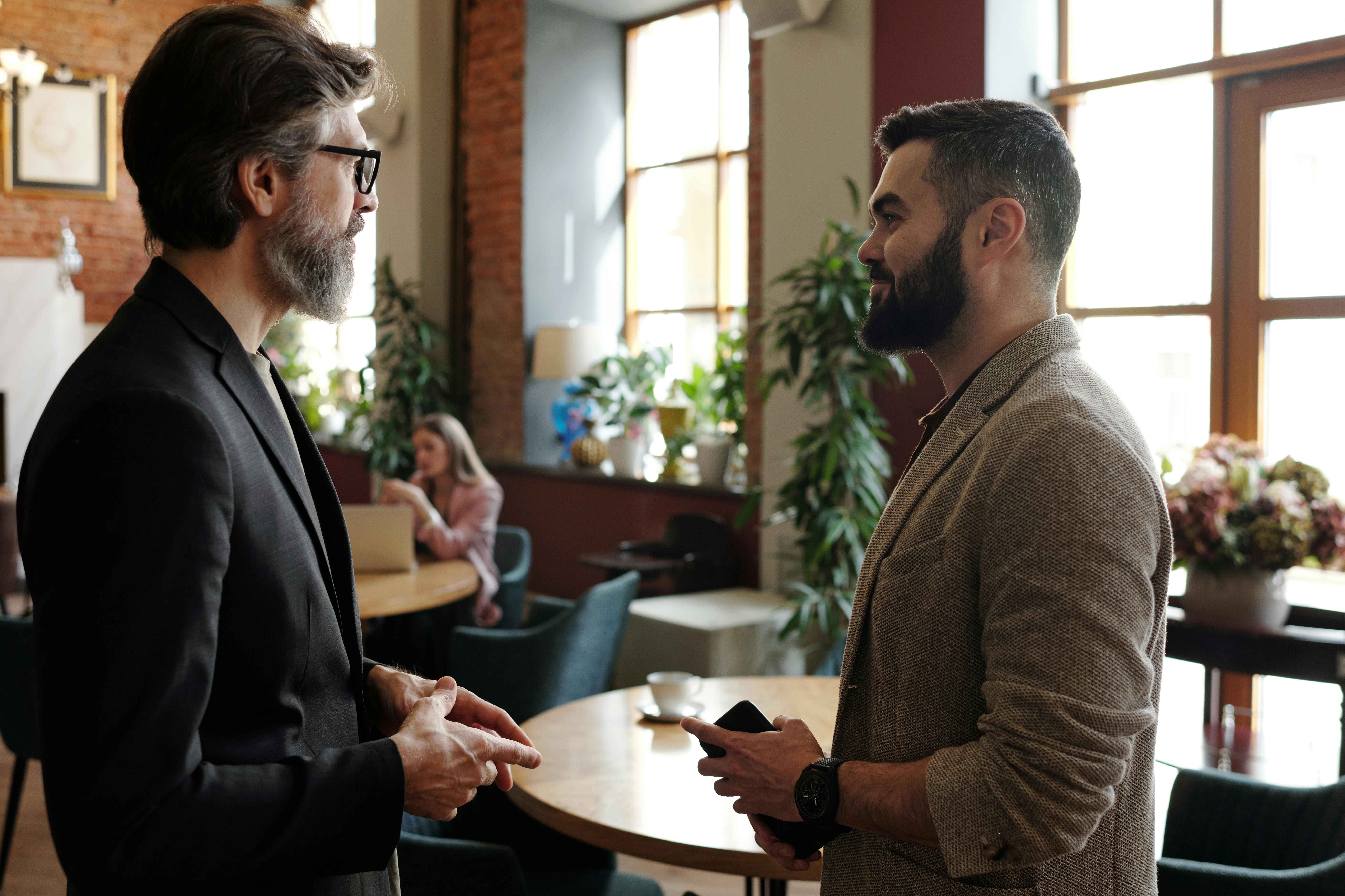 Due professionisti che discutono in un contesto lavorativo informale, immagine di un networking basato su confronto reale e scambio di valore.