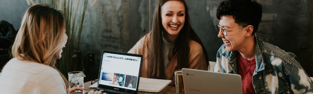 People laughing gathered around a laptop