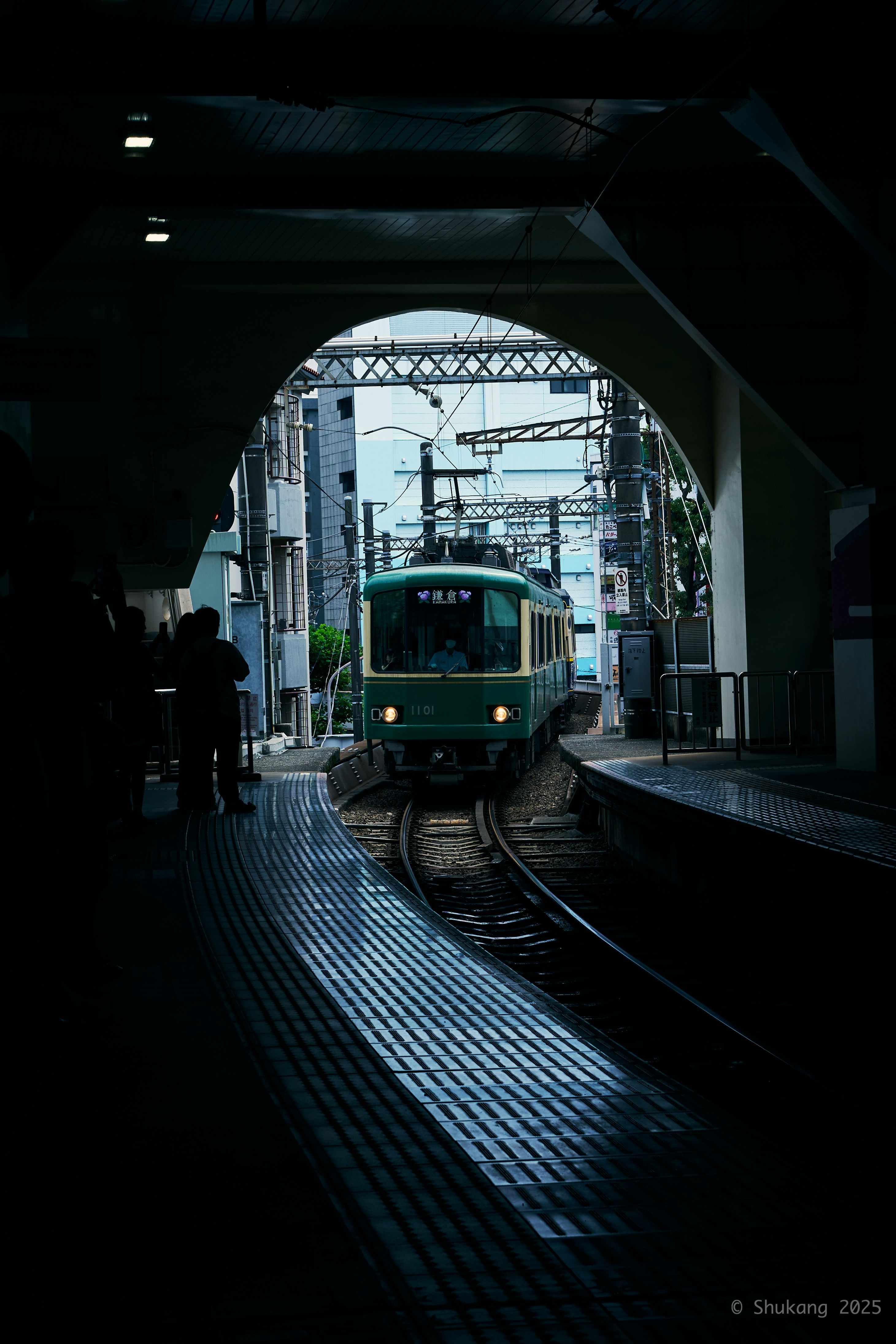A green train arrives at the platform.