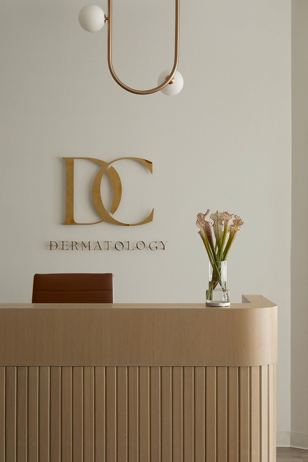 Branded reception desk with gold metal logo signage in a modern DC dermatology office.