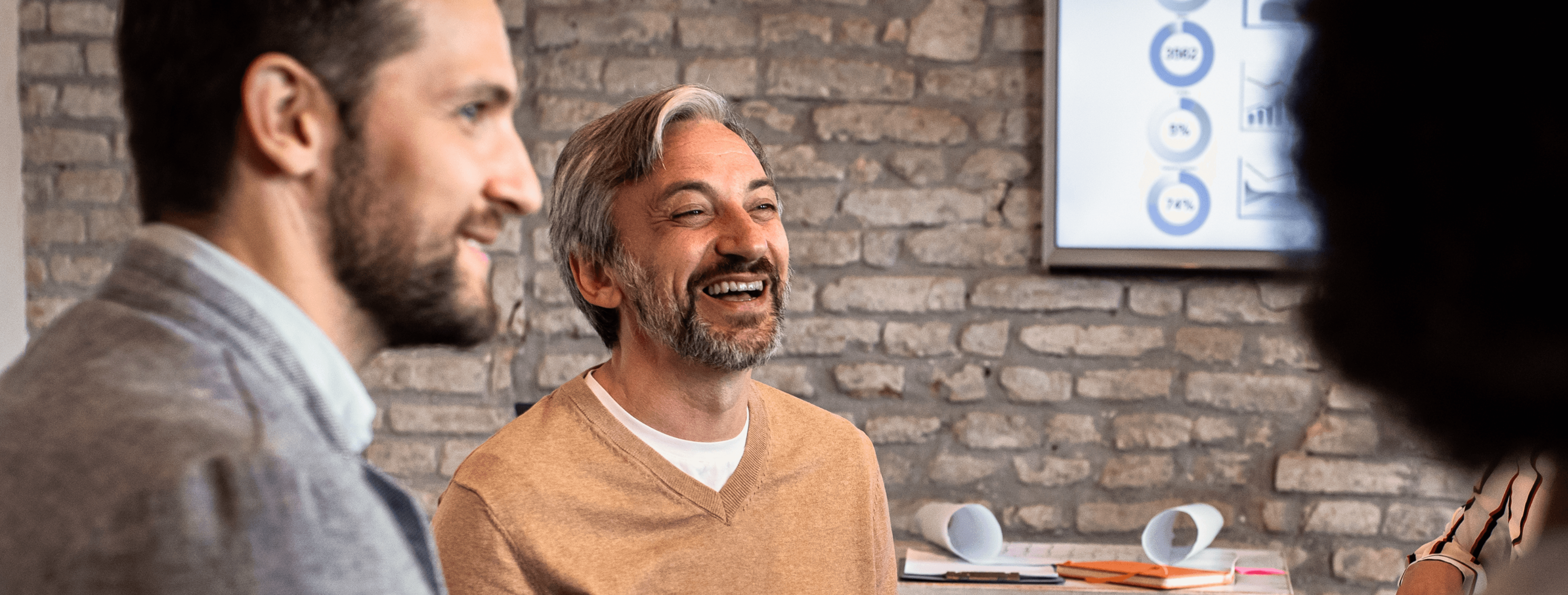 Professionals in a meeting with one person smiling, representing positive workplace culture and collaborative discussion.