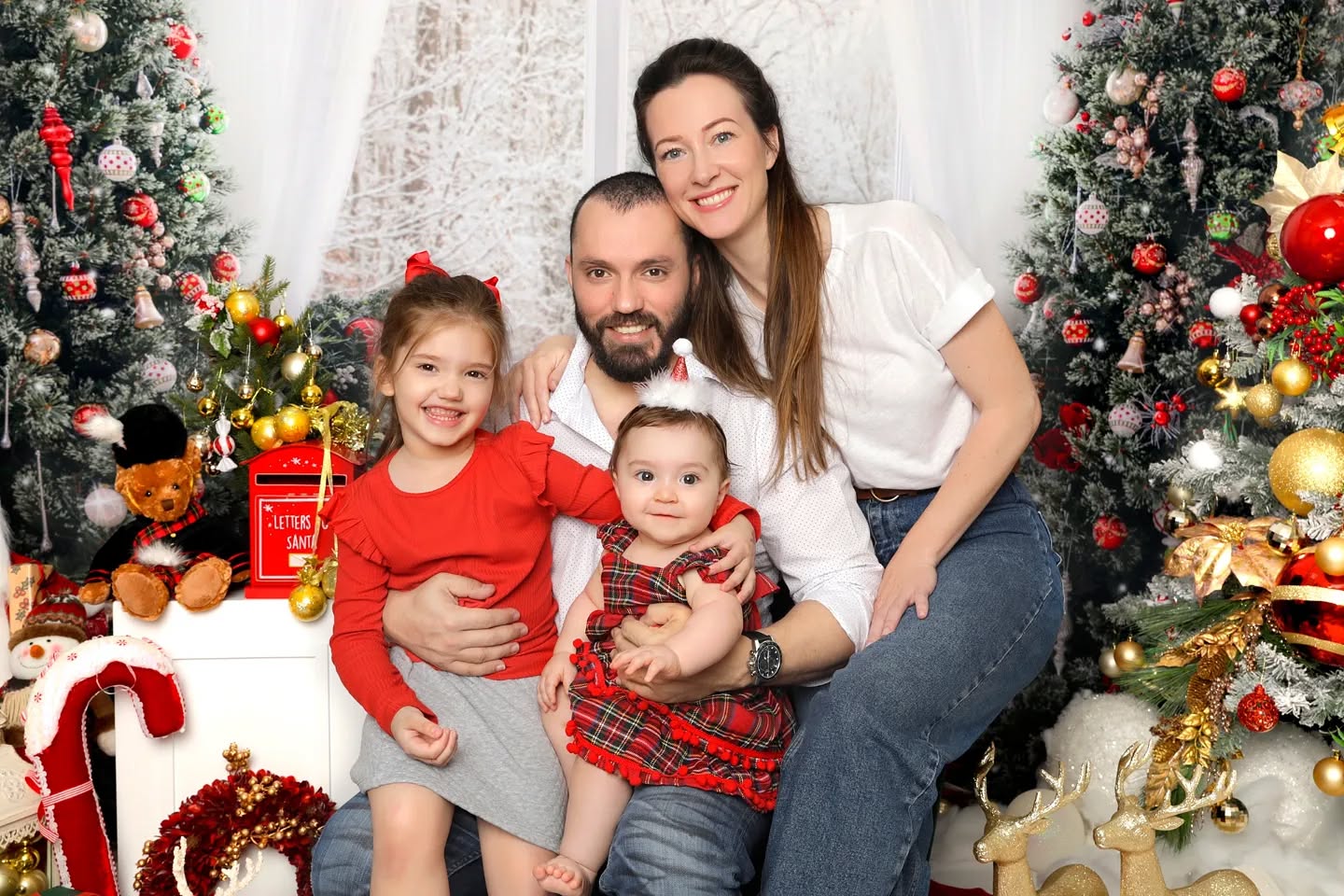 Happy family smiling and posing for their Christmas photos with a festive set up captured by Mahvin Photography in Dubai.