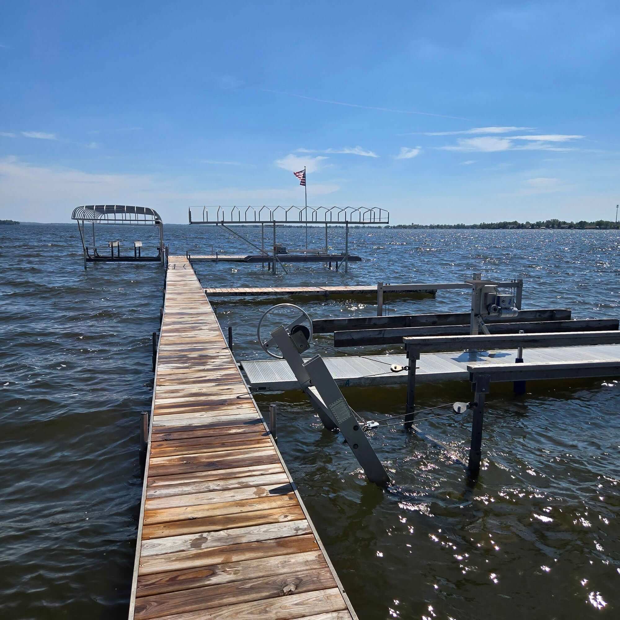 Four boat hoists installed alongside a community dock extending into Houghton Lake, Michigan.