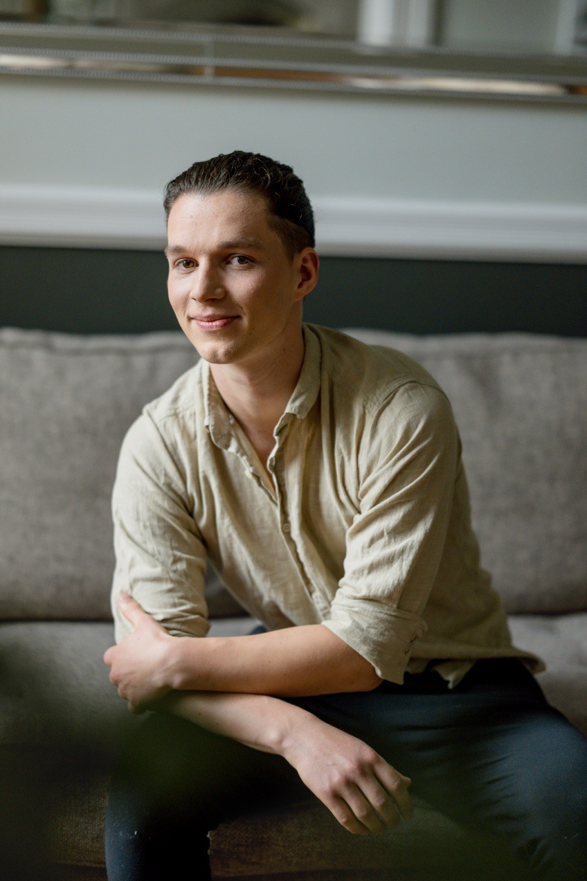 Smiling person seated indoors — founder of Seven Life Areas, offering guidance for living with clarity, harmony, and purpose.