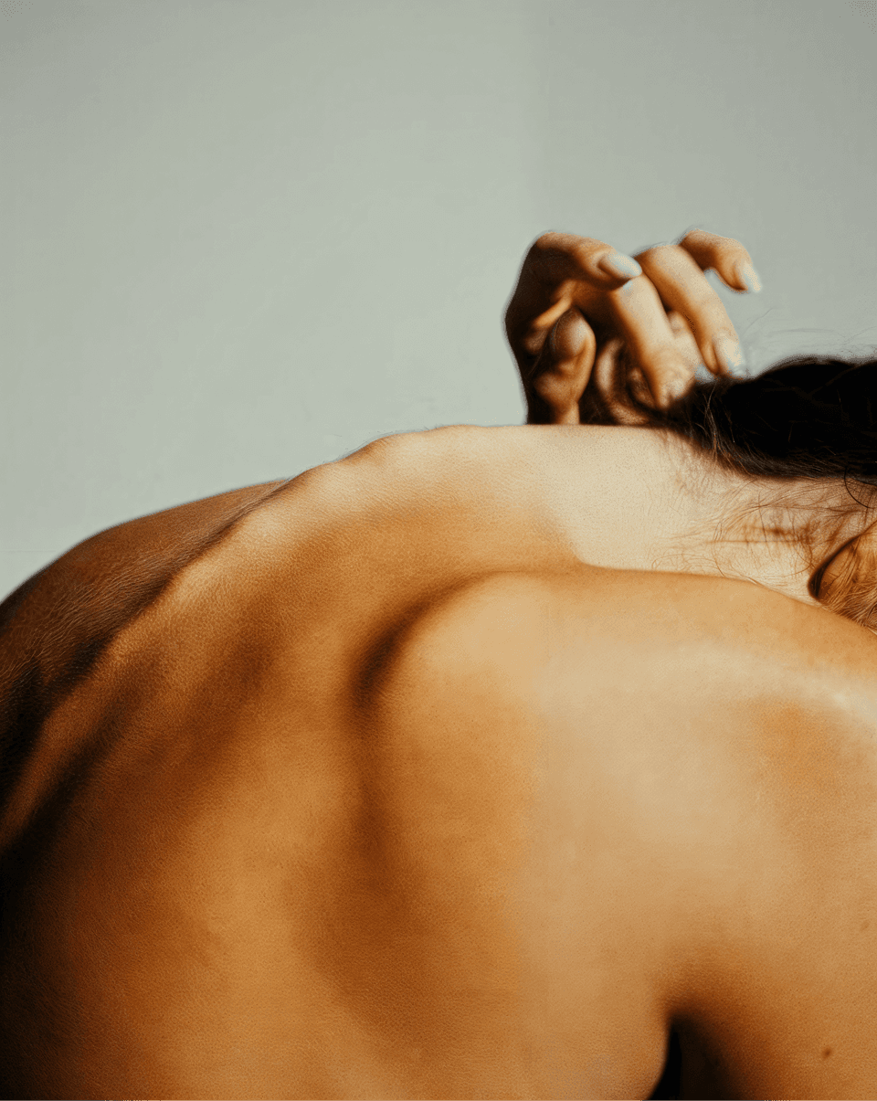 A woman lying down with a towel wrapped around her head, her face glistening with facial oil. Her eyes are closed, and she appears to be enjoying a spa treatment in a peaceful setting.