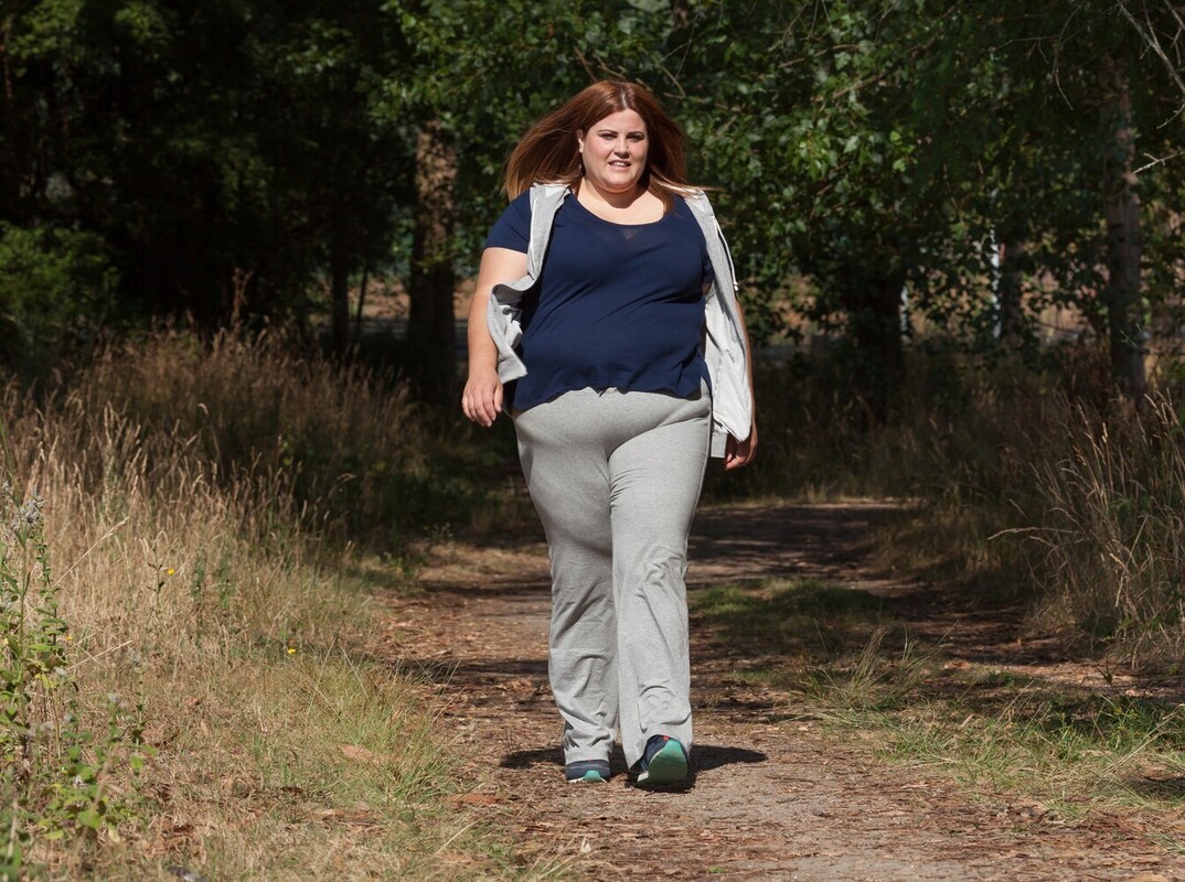 woman doing a walking pace to lose weight that works for her body down a forest path