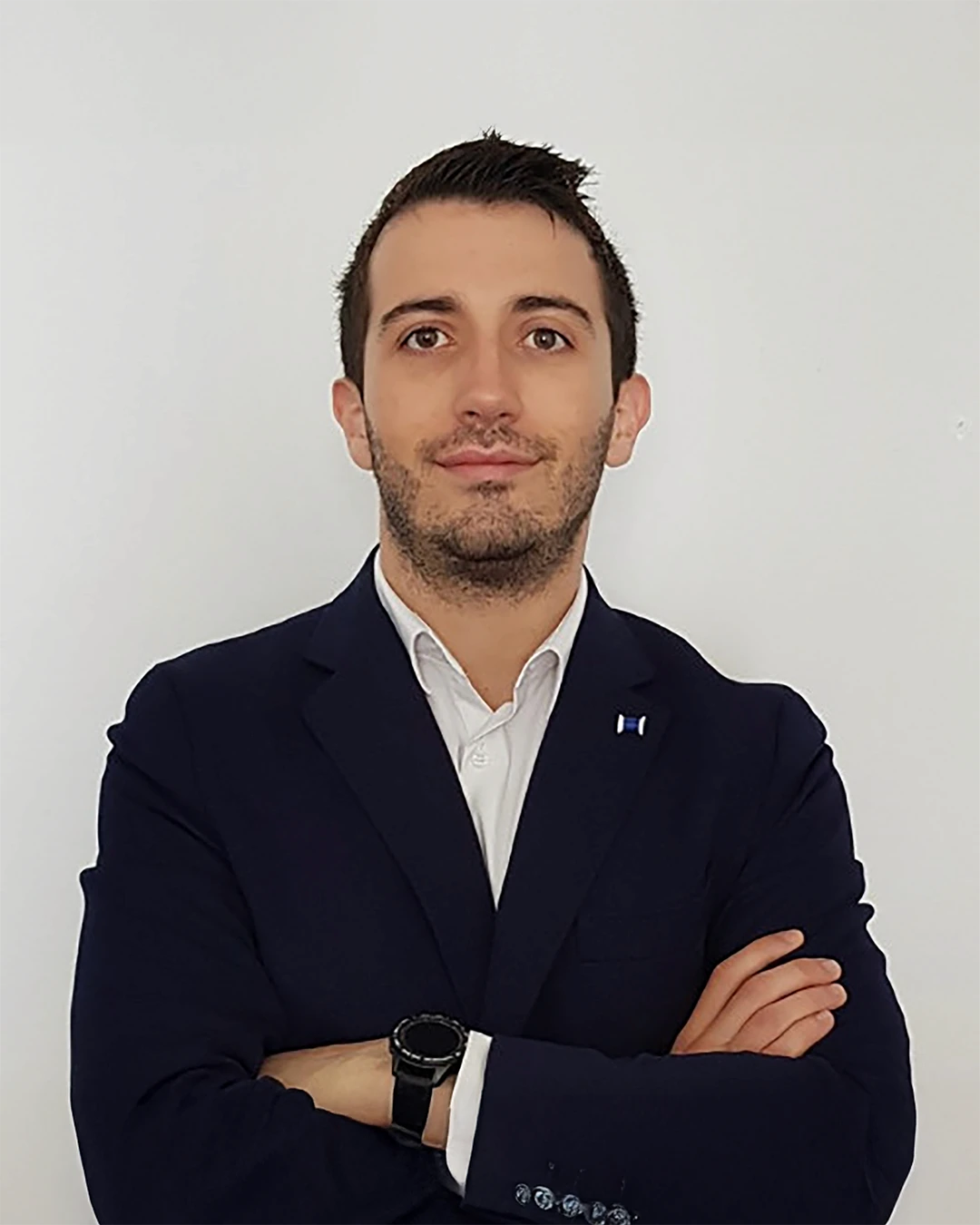A young man with dark hair smiles at the camera, set against a modern indoor background.