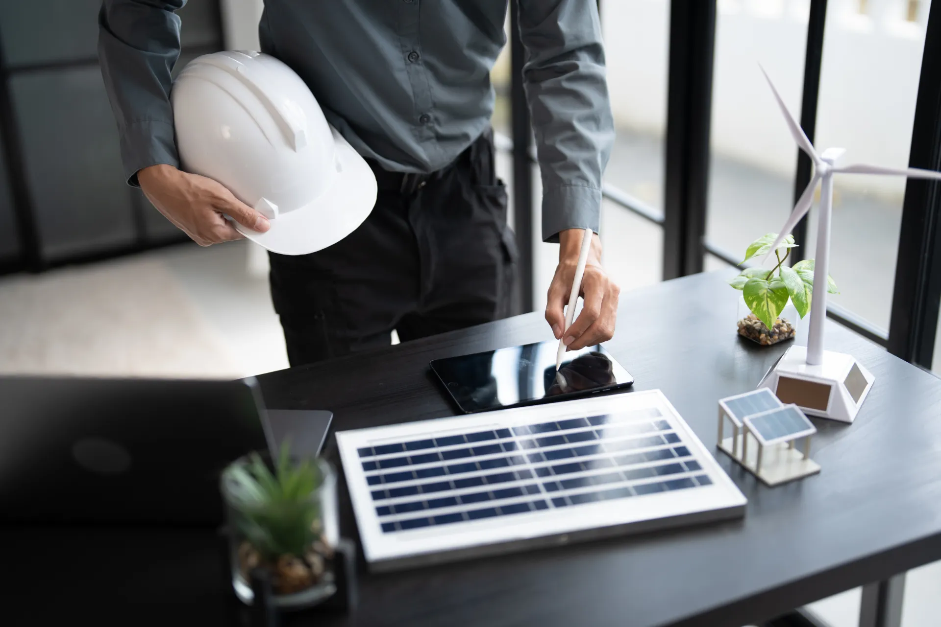 Eine Person die vor einem Schreibtisch steht und eine Photovoltaikanlage zeichnet.
