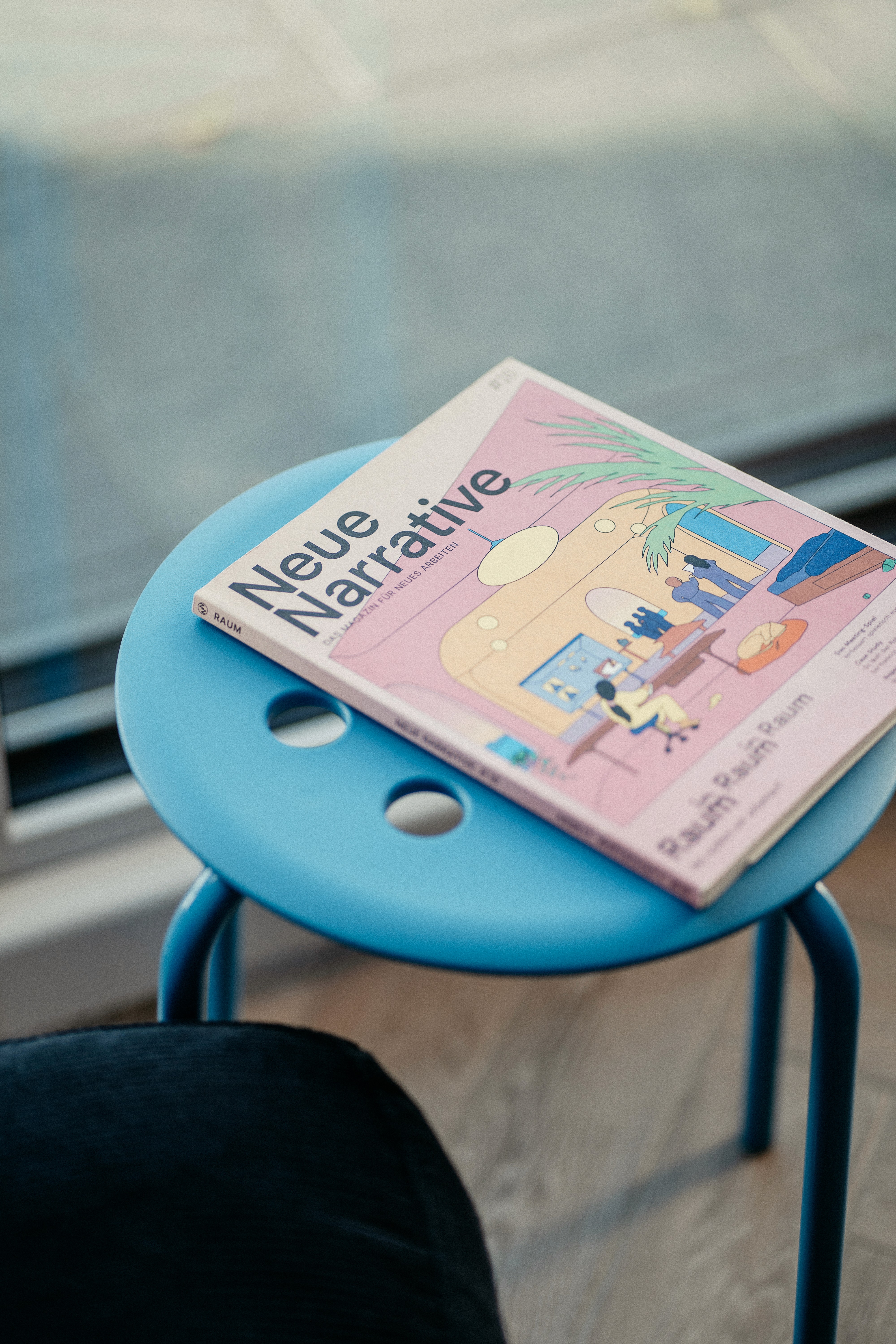 Magazin mit dem Titel 'Neue Narrative' auf einem blauen Hocker in einem Coworking Space
