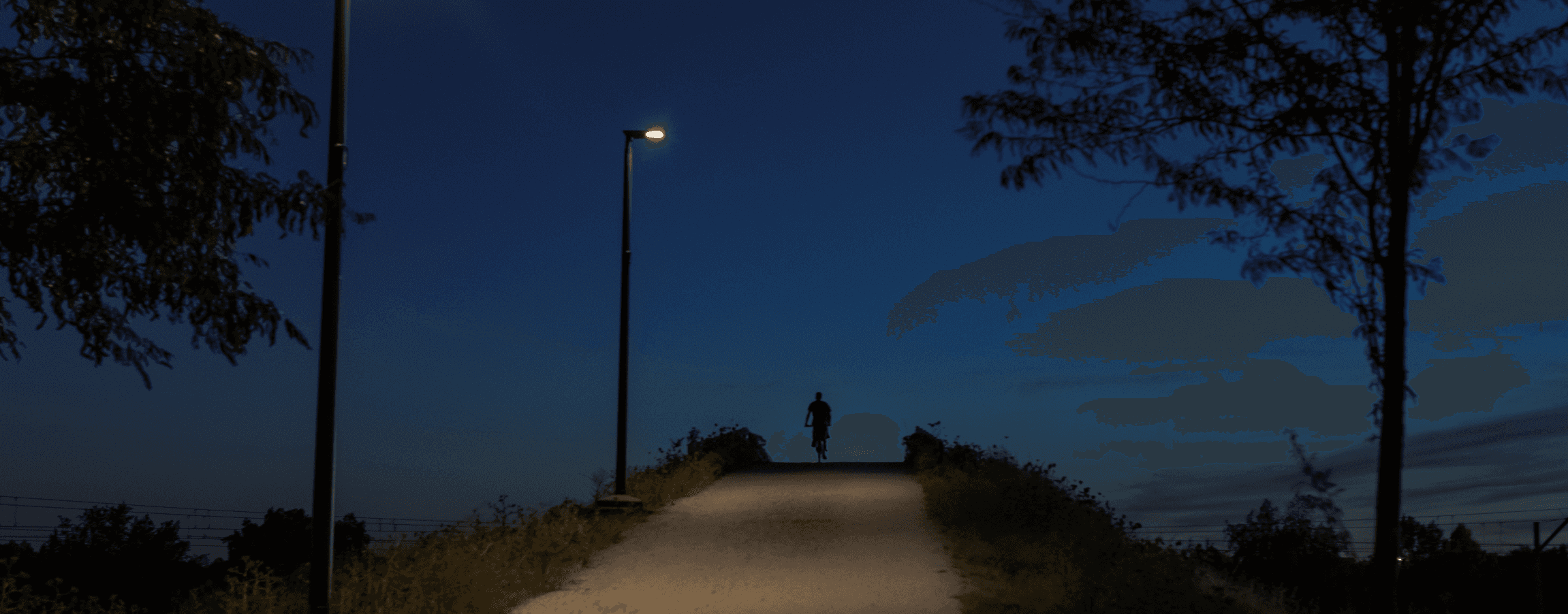 Photo of a person riding a bike at night under a streetlight