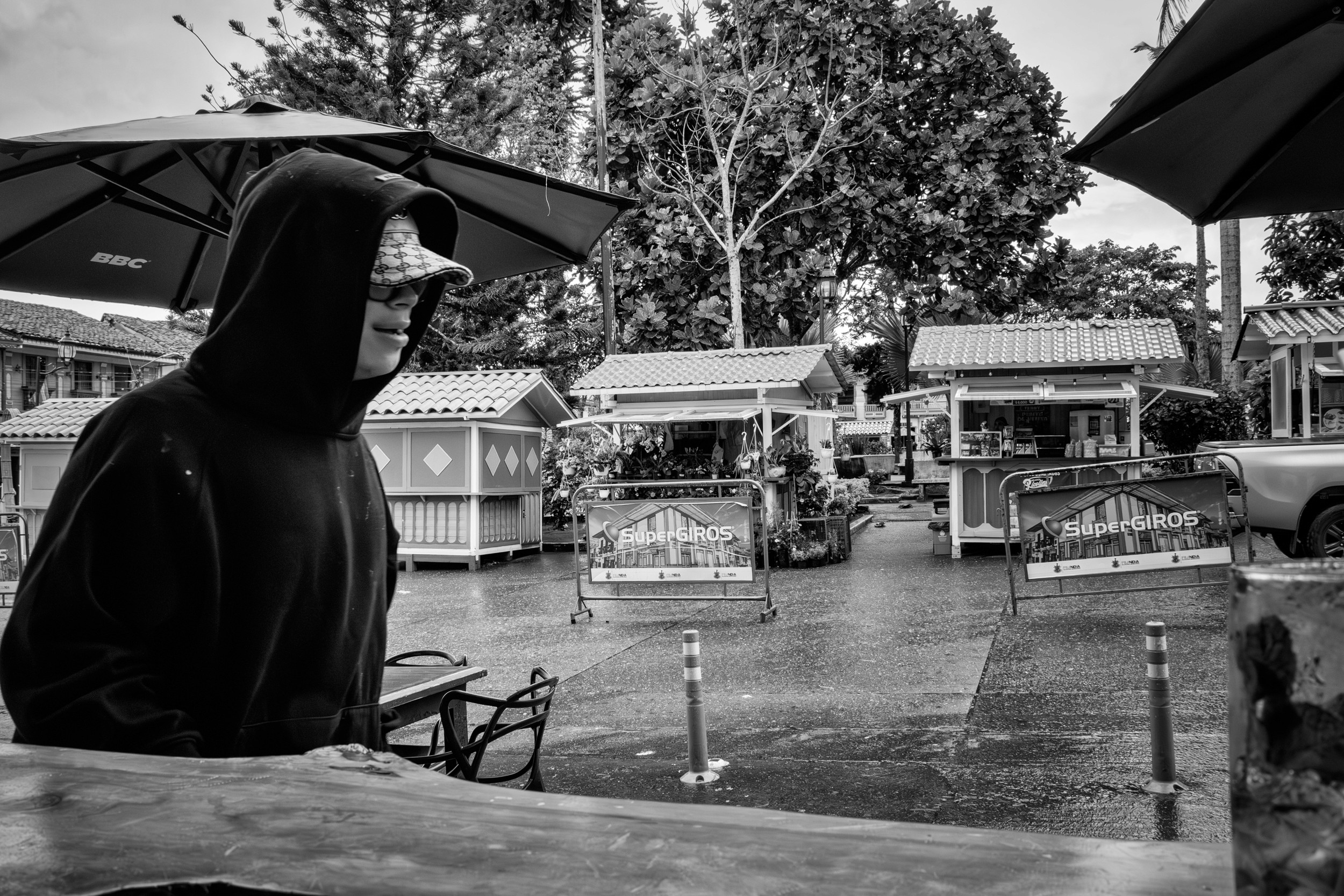 Rainy street scene with people passing by a bar window.