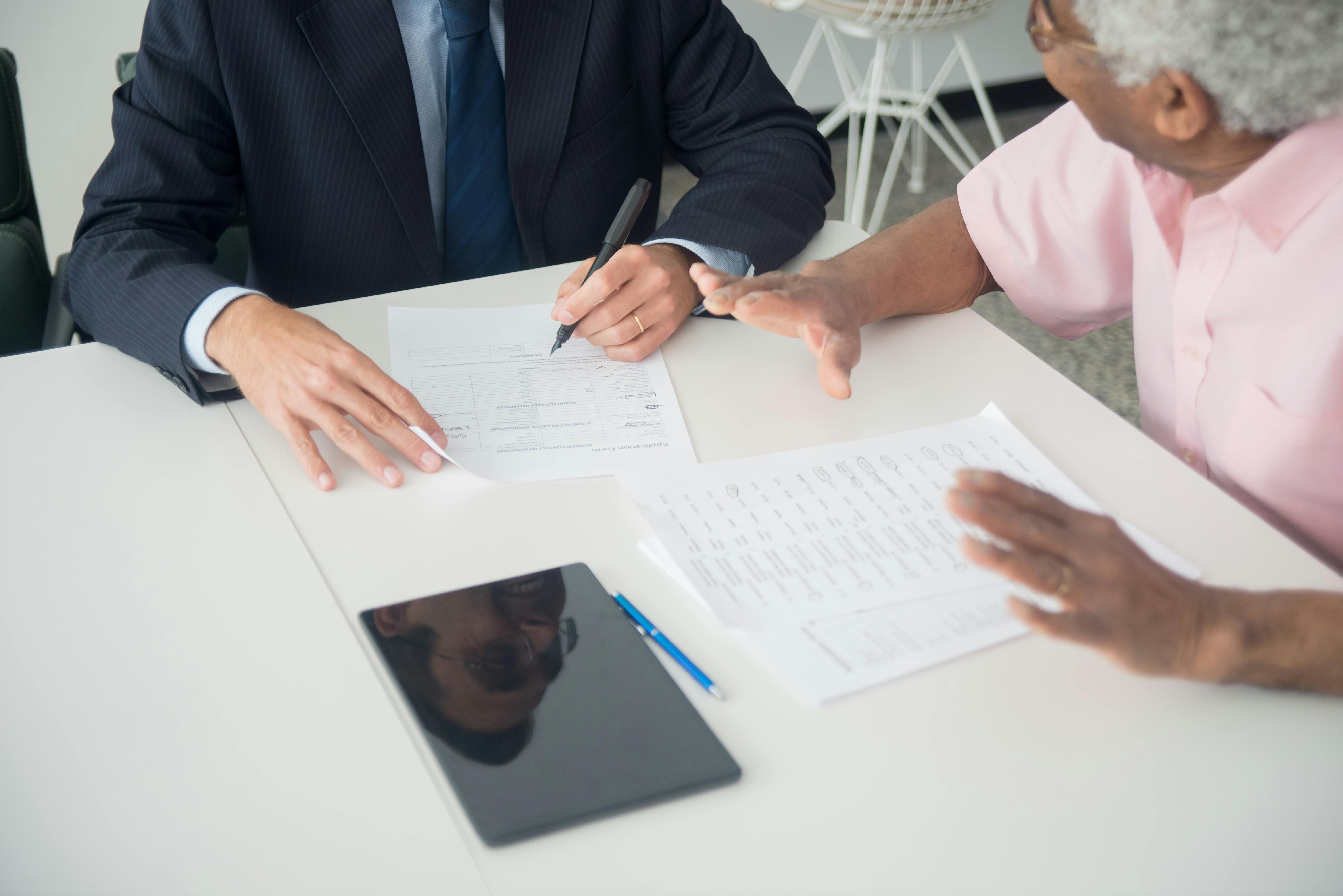 Professional consultant helping senior man with paperwork in office meeting