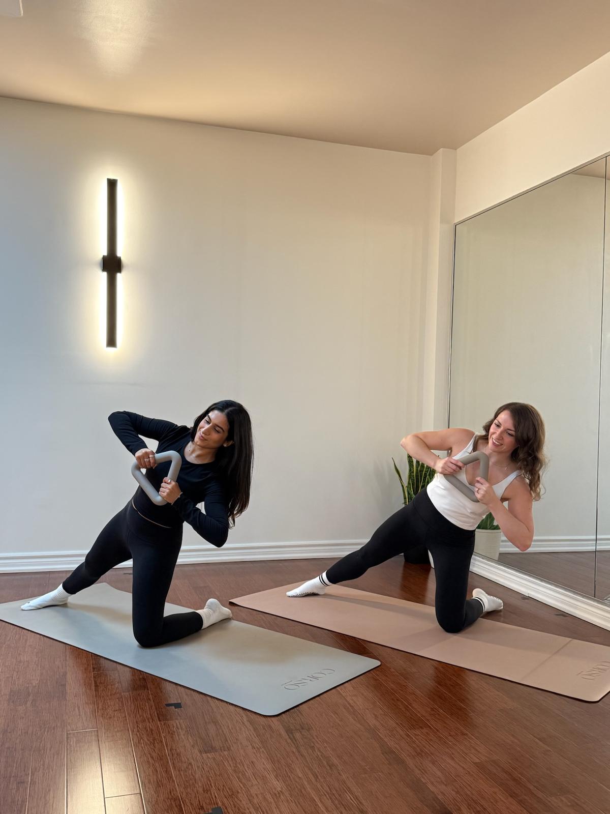 Two women doing a challenging a mat flow class with intention, in Toronto