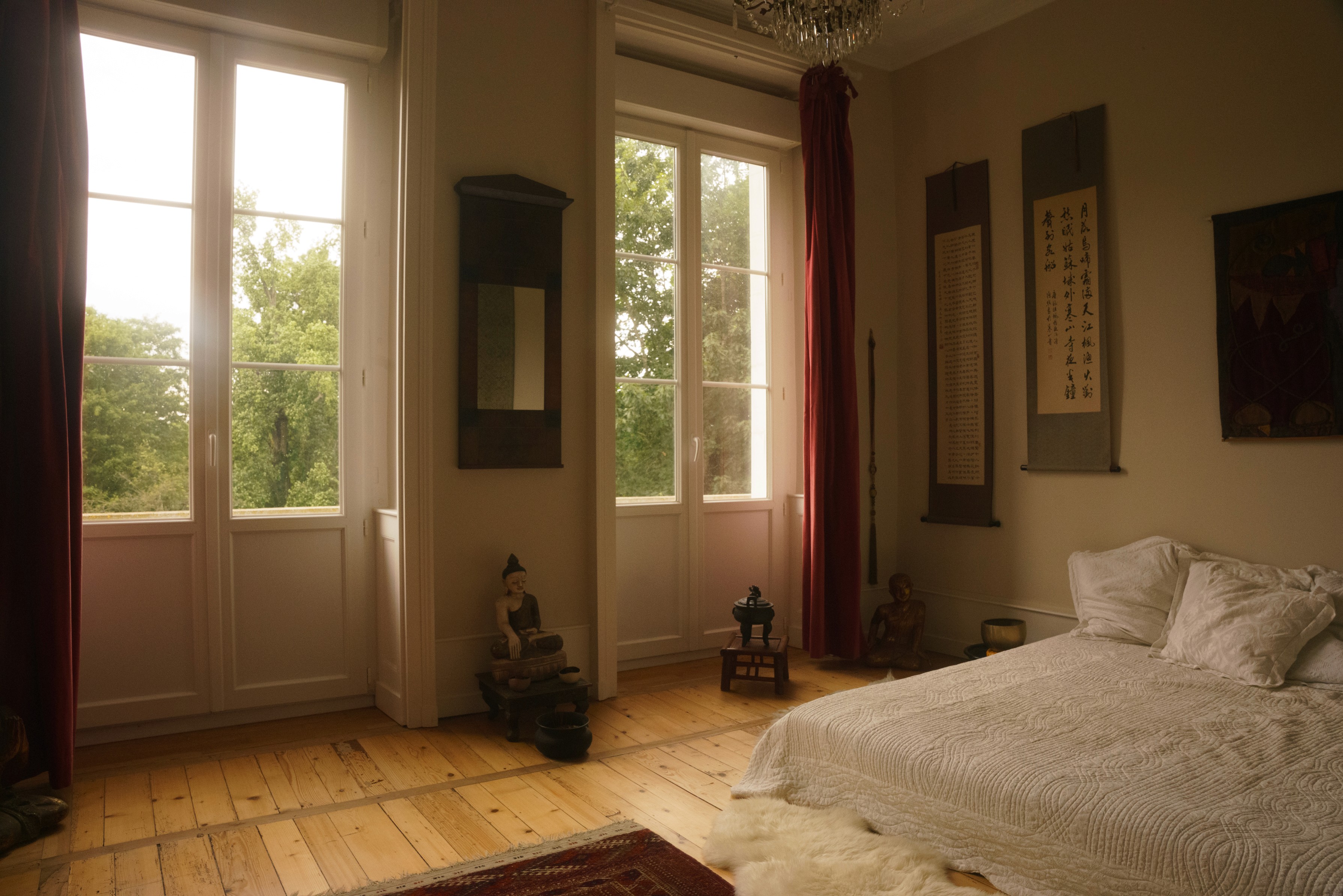Bright bedroom with tall shuttered windows and wooden floors