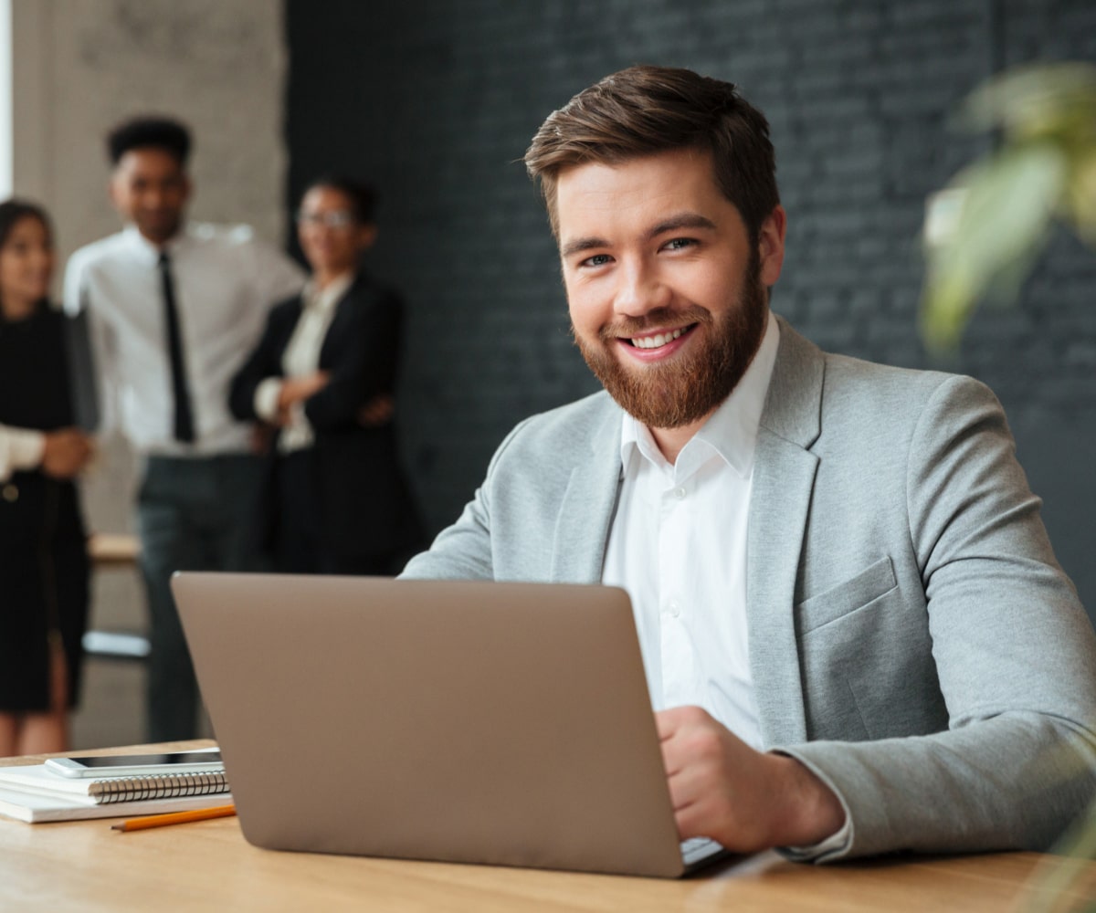 A workspace with tax forms, a calculator, a pen, an envelope, sticky notes, and a cup of coffee on a dark desk.