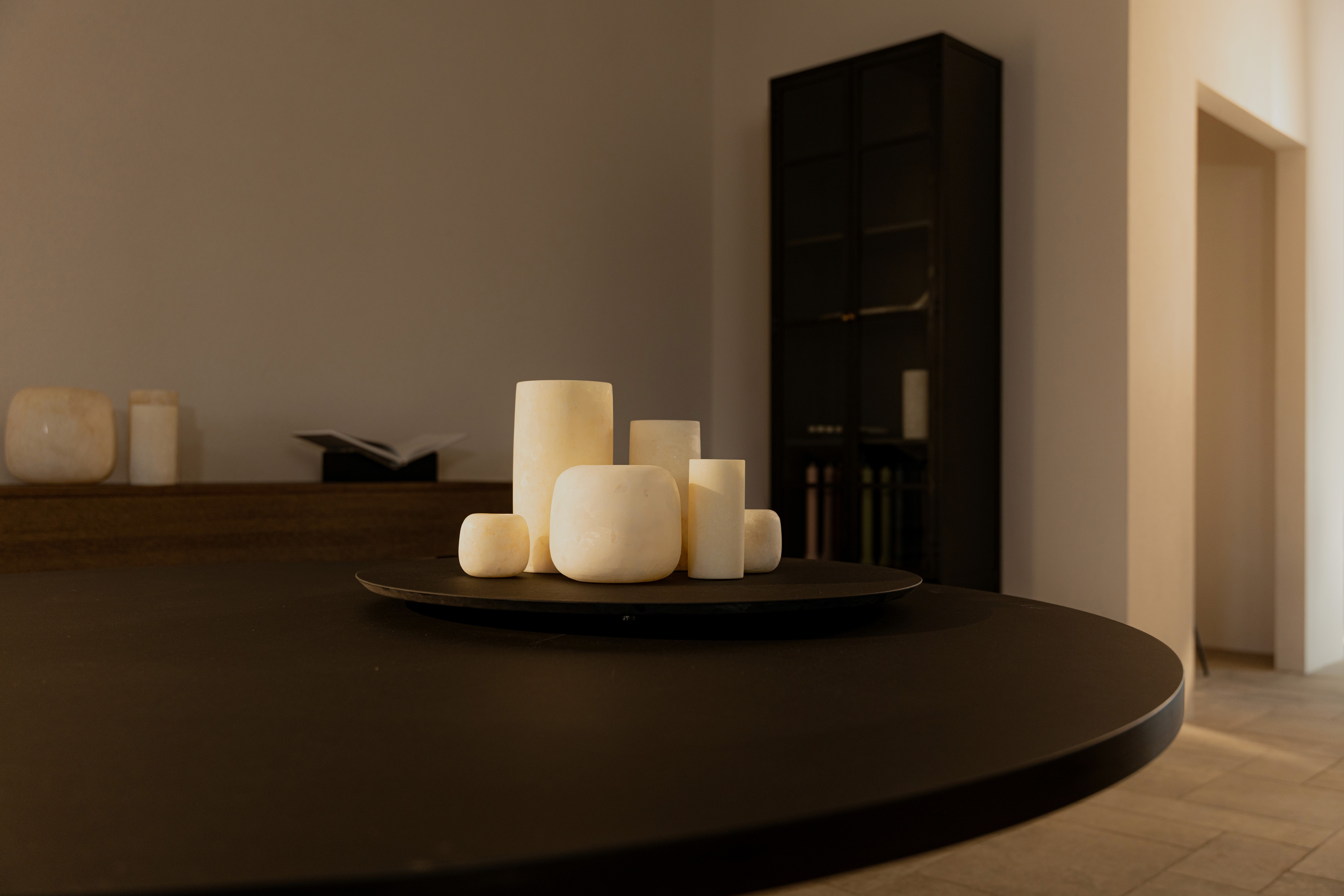 Cluster of white VIGT candles on a dark round table in a dim interior