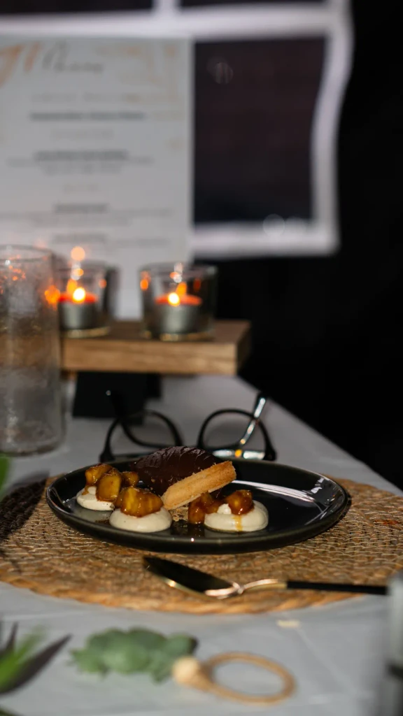 A dinner table laid with candles, the printed menu and dessert