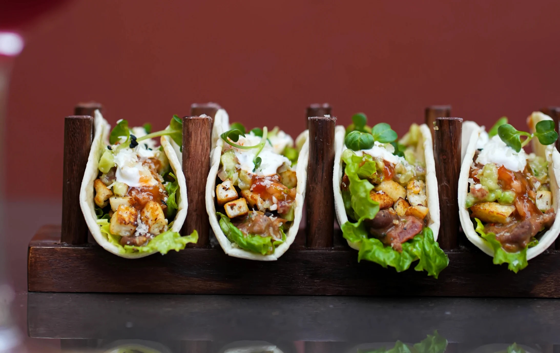 Tacos in a wooden holder and one being held