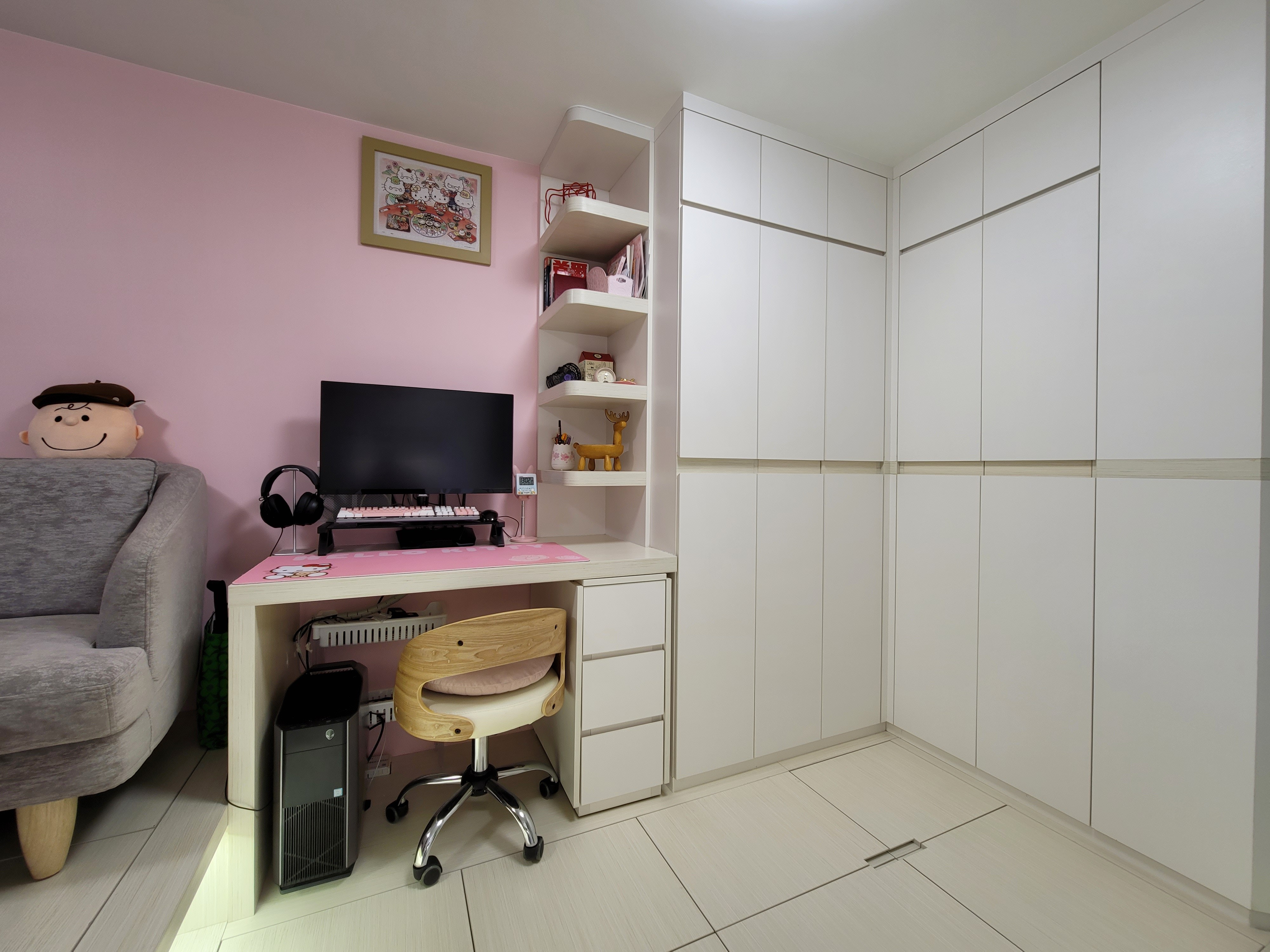 Organized home office workspace featuring white built-in shelving and high-gloss storage cabinets to create visual depth in Hoi Tat Estate.