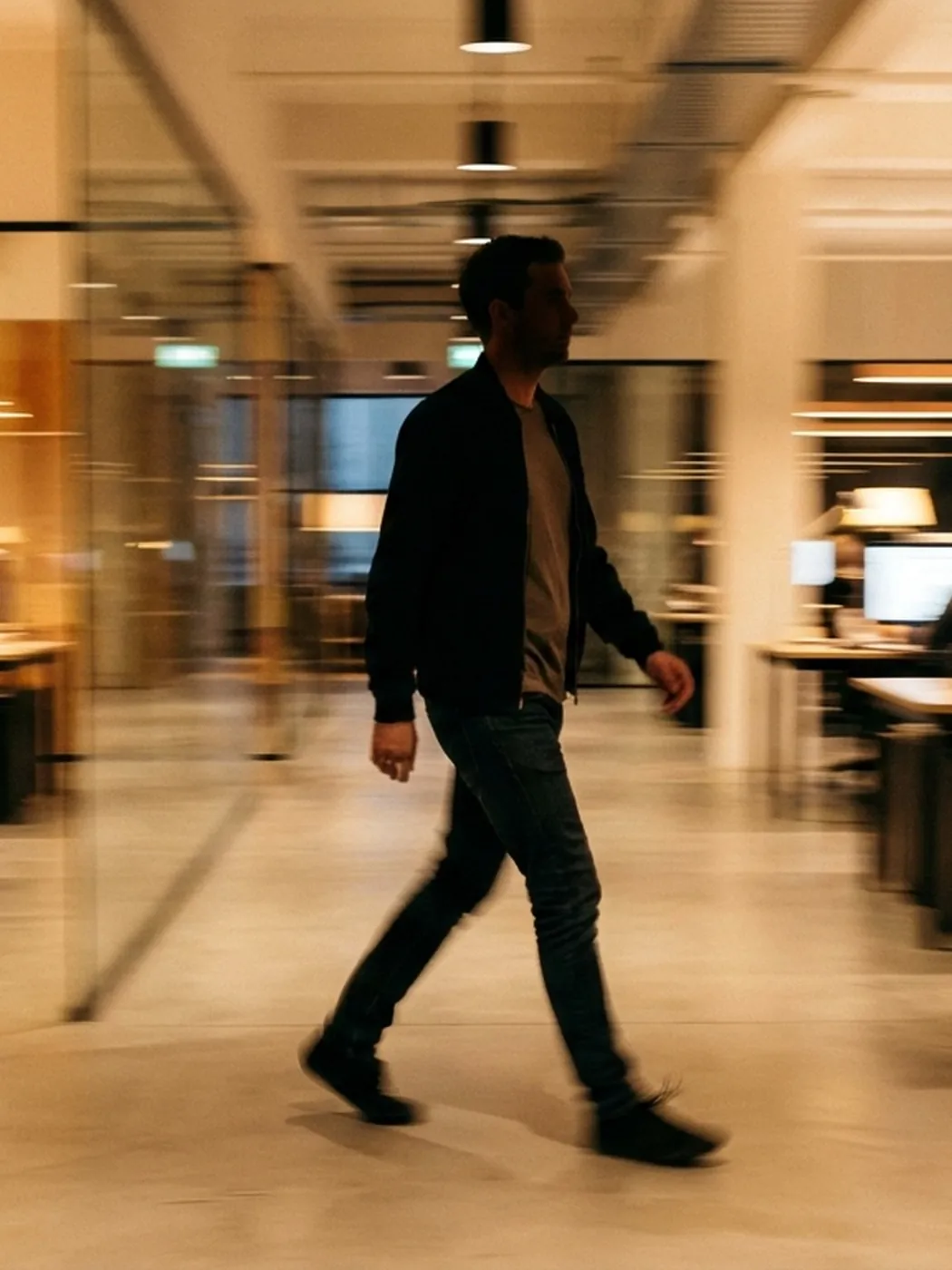Man walking in a blurred office hallway.