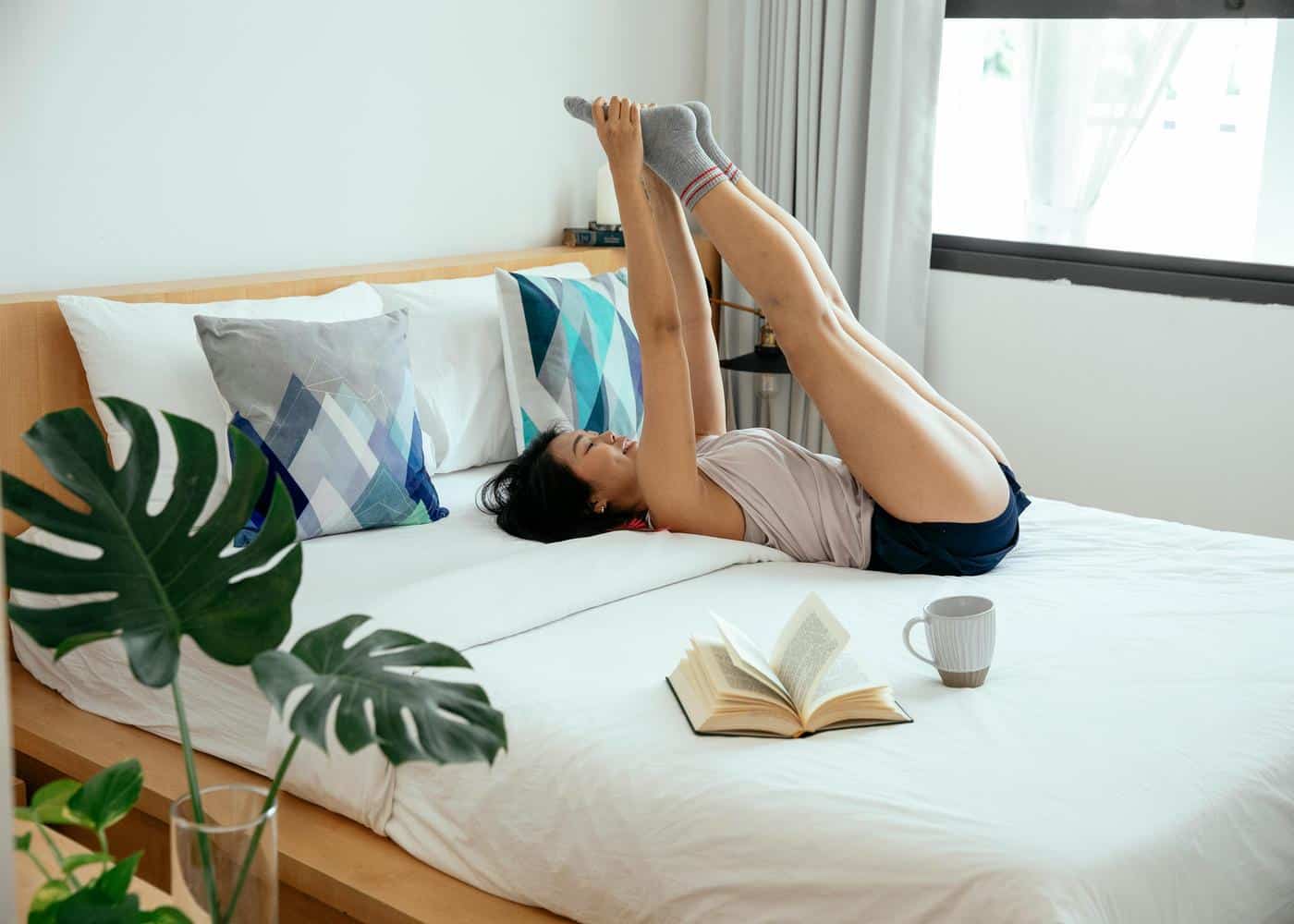 Woman exercising in bed by holding her legs in the air