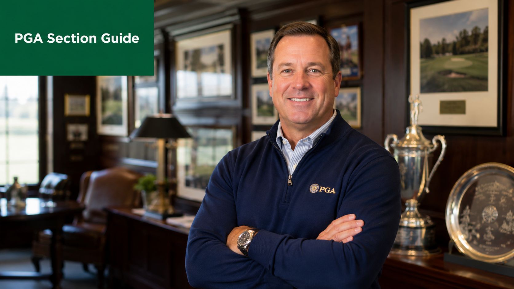 A professional portrait of a man smiling in a navy sweater inside a wood-paneled office.