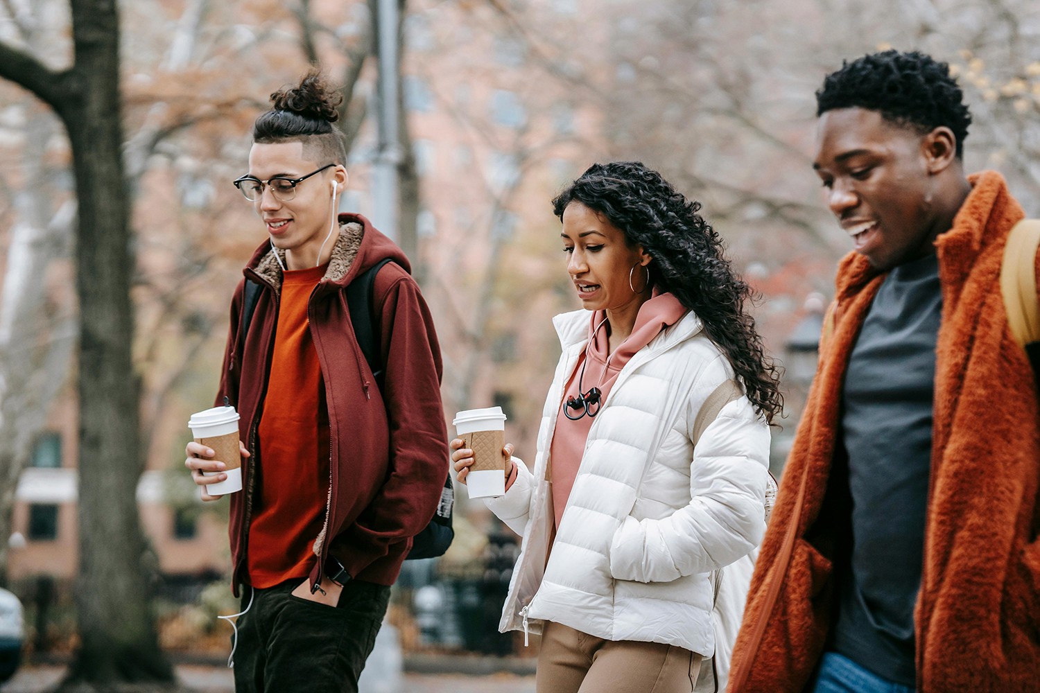 Three multiracial people walking in the woods. Smiling. Happy