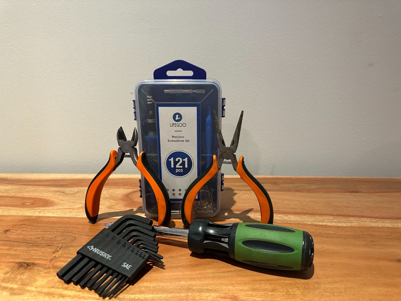 Kit d'outillage de précision LIFEGOO de 121 pièces avec pinces, clés hexagonales Husky et tournevis multifonction, posé sur une table en bois