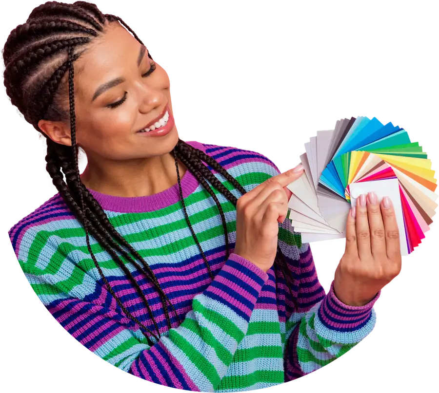 A woman smiling while holding vibrant colour swatches in her hand, contemplating her design choices.