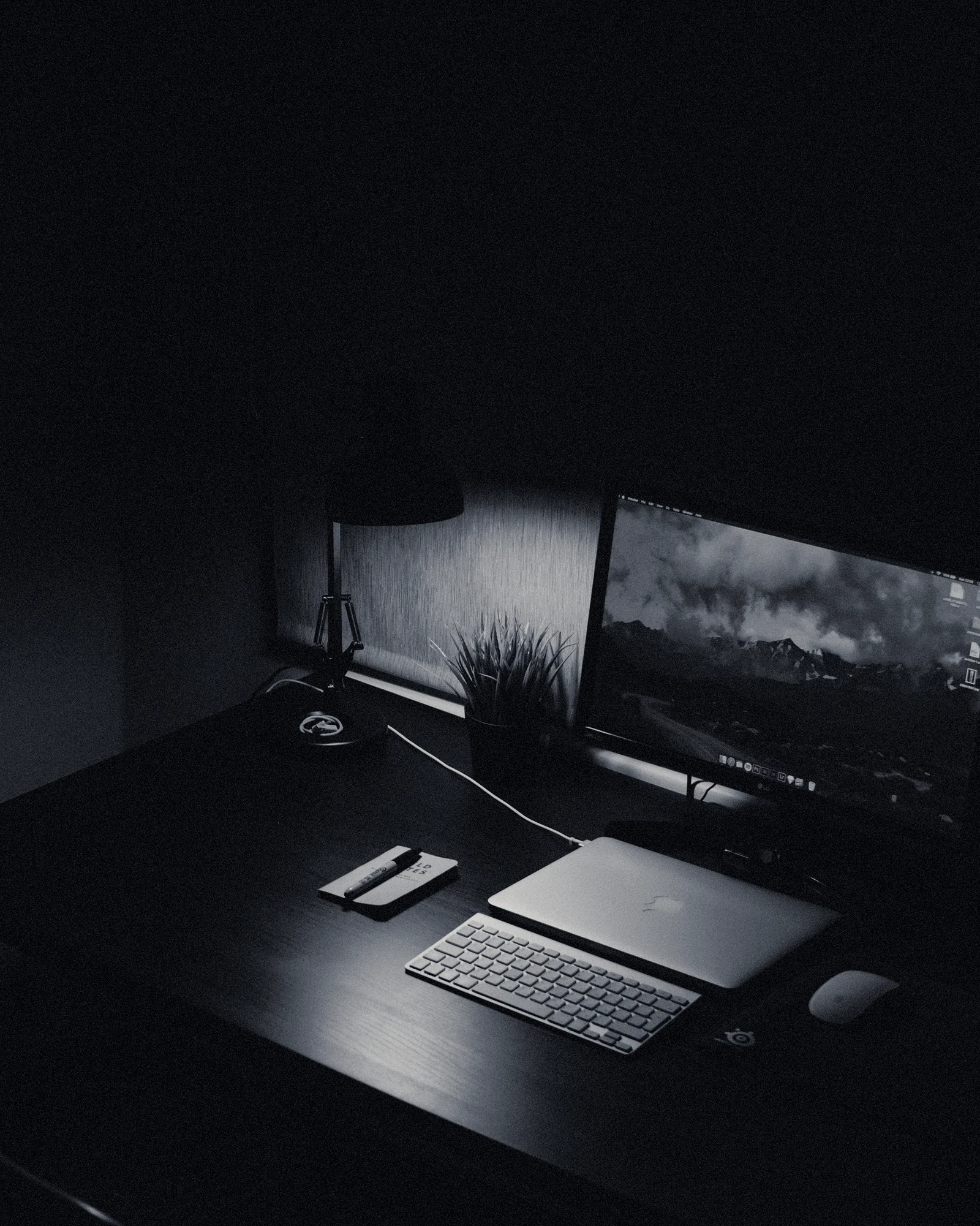 A dark desk lit by a monitor and a lamp