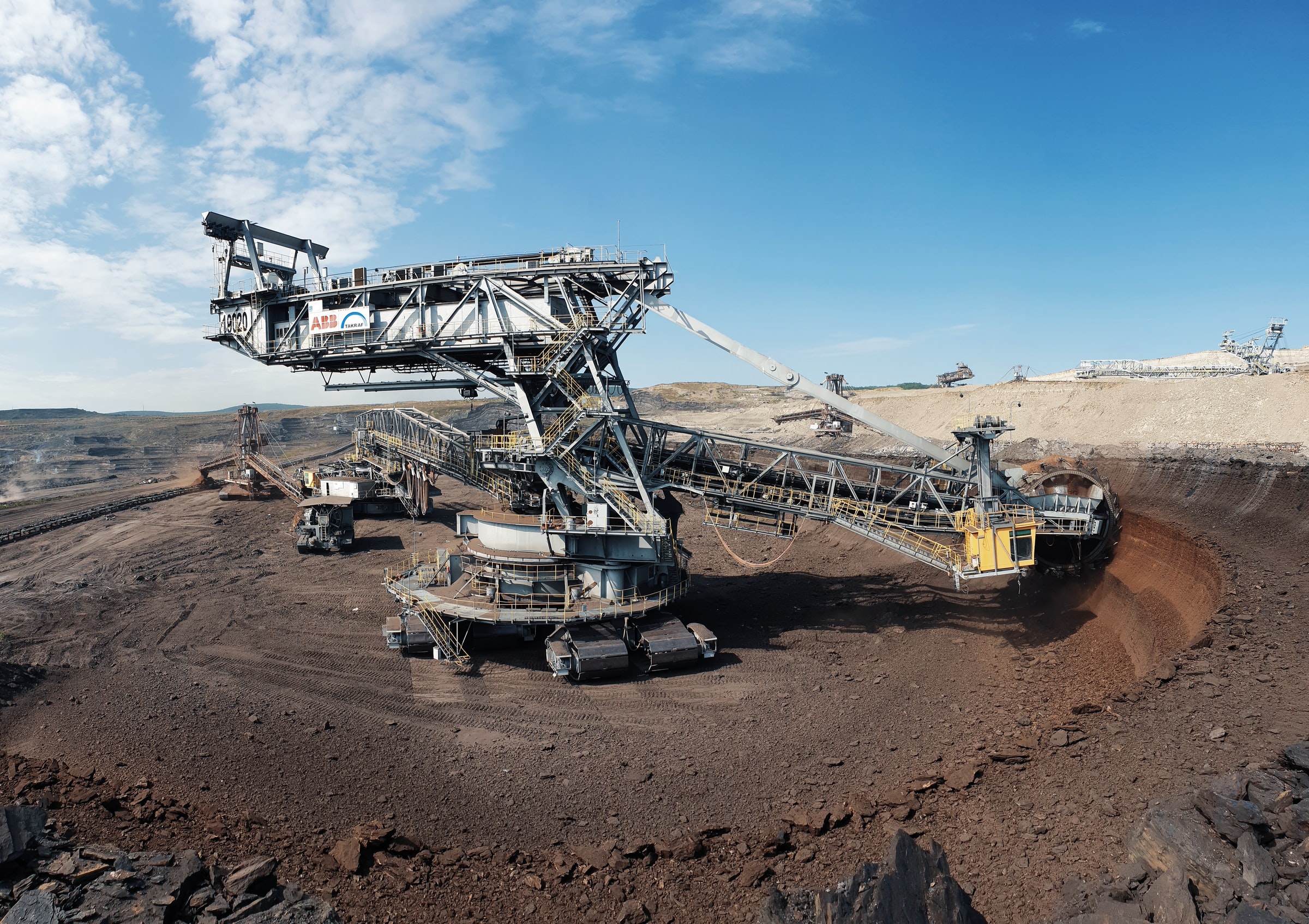 Large bucket-wheel excavator operating in an open-pit mine under blue sky, illustrating industrial mining activity for a blog about high-yield mining stocks