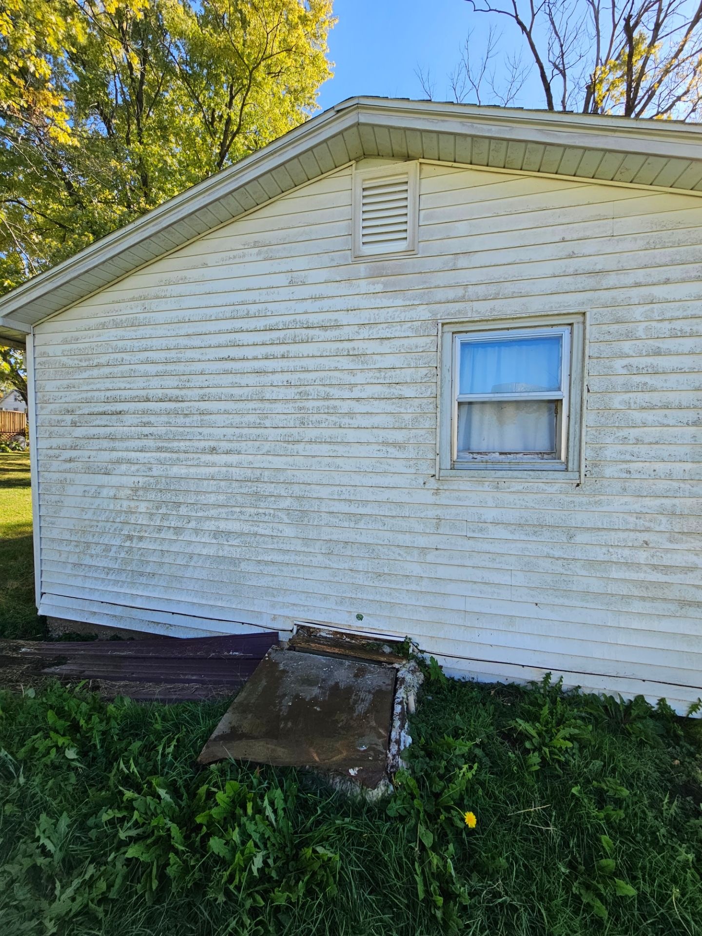 House siding with algae and dirt buildup before pressure washing