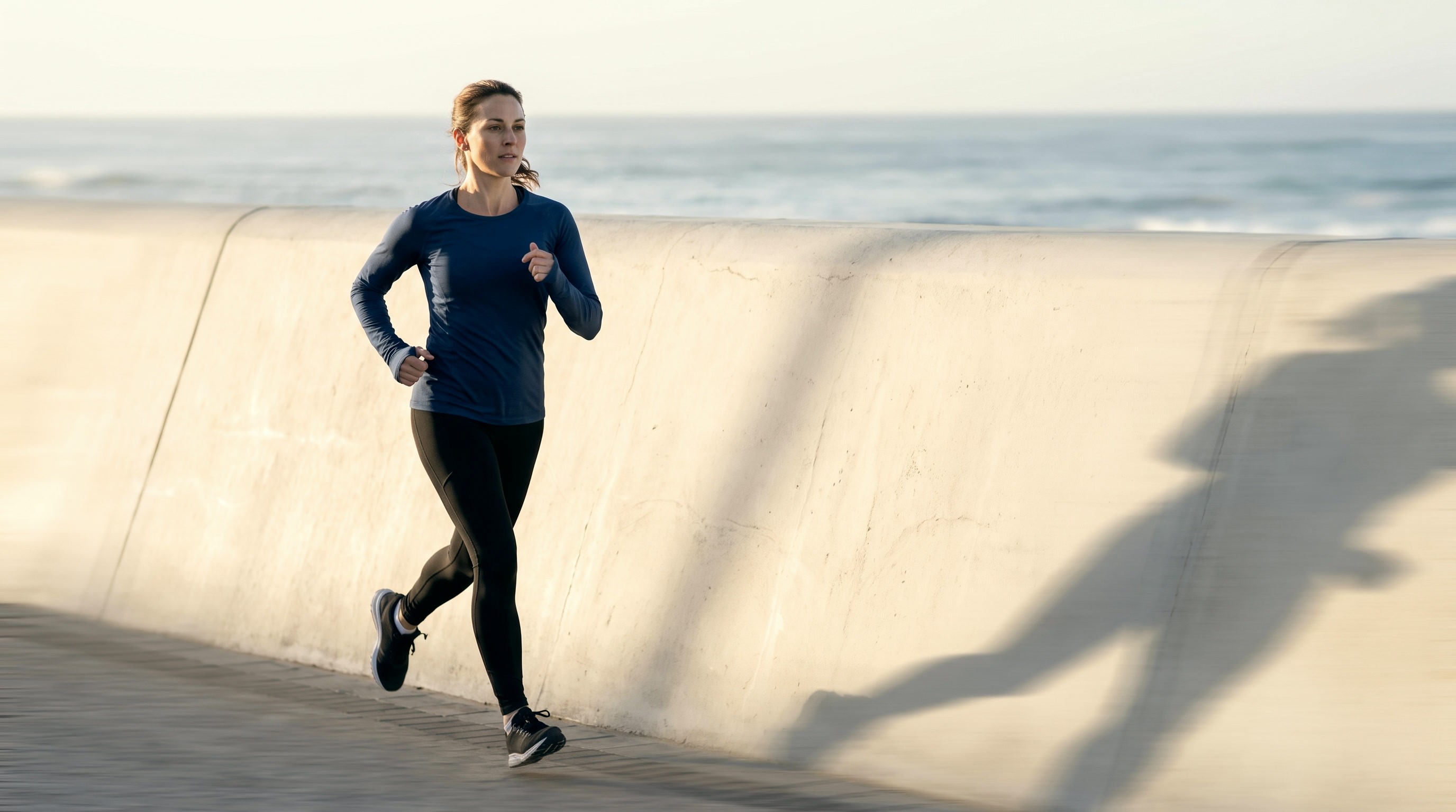 Läuferin joggt am frühen Morgen an einer Betonmauer entlang