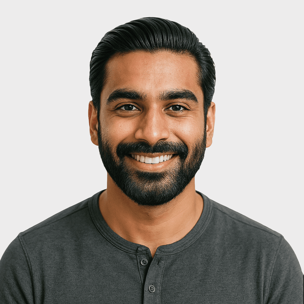 A smiling man with dark hair and a beard wearing a gray shirt.