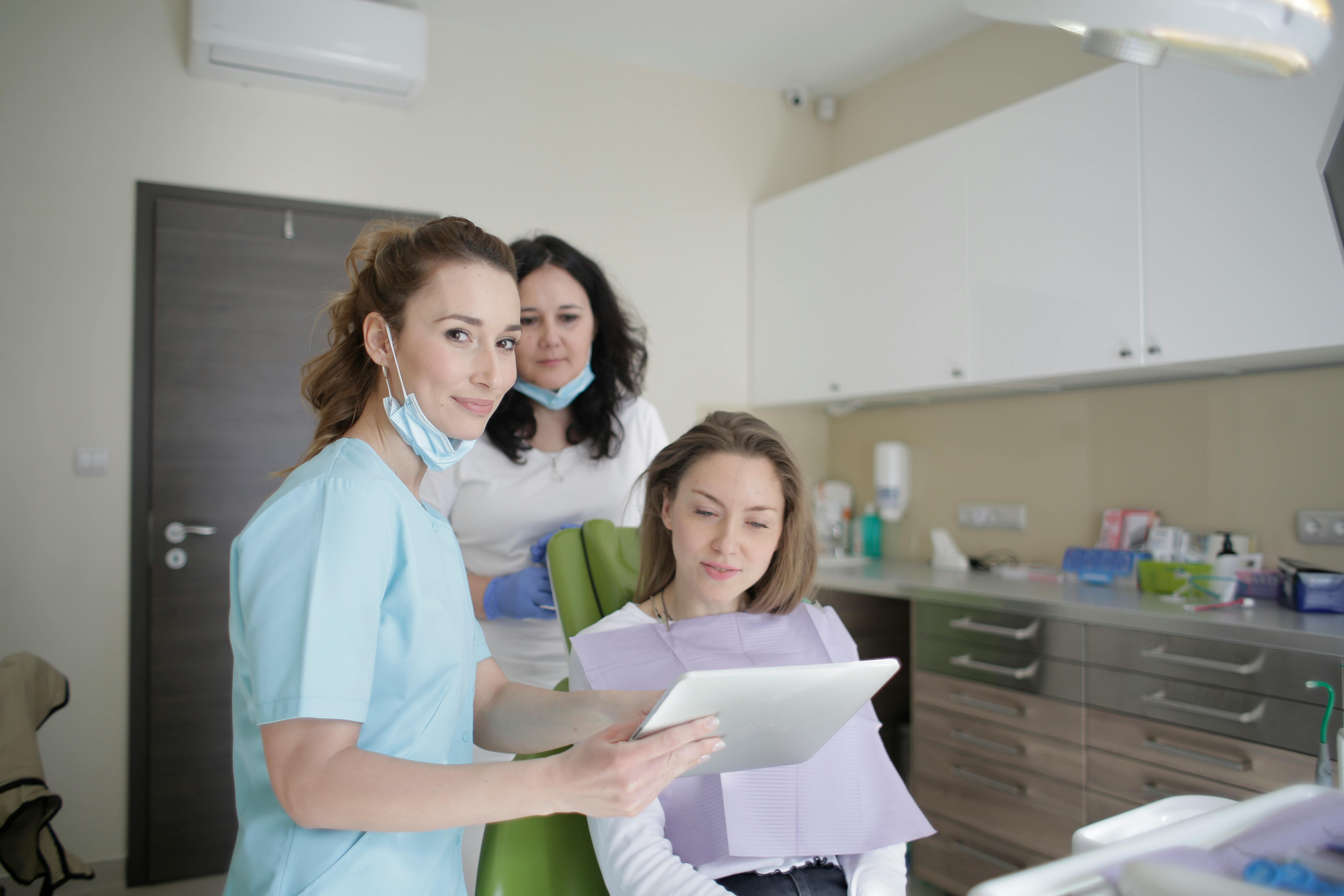 dental hygienists helping dental patient in chair
