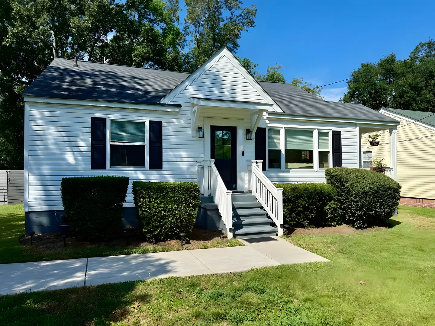 White cottage with black shutters and a covered front stoop at the Park Circle Charmer in North Charleston