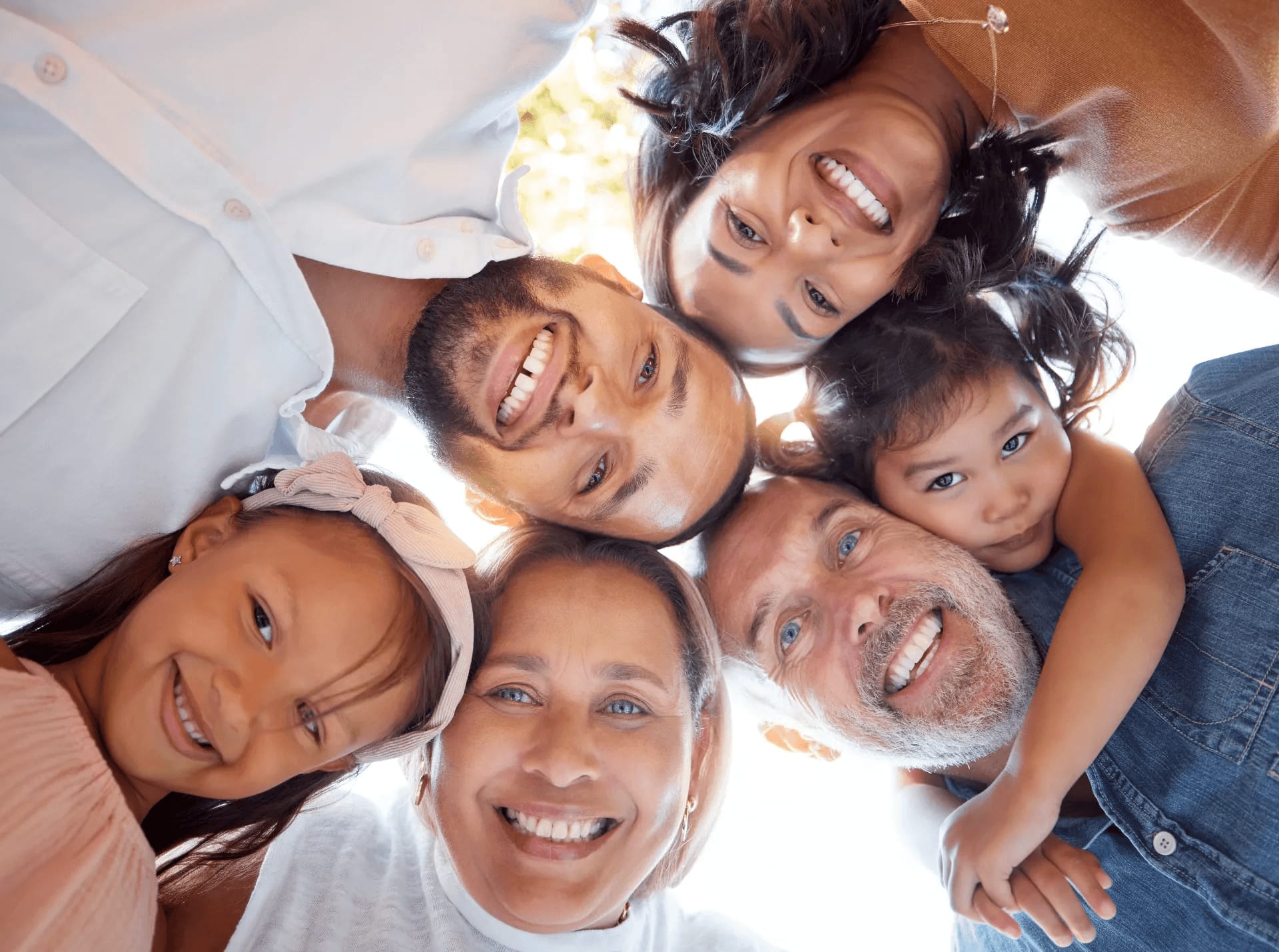A family gathered in a circle, smiling down at the camera
