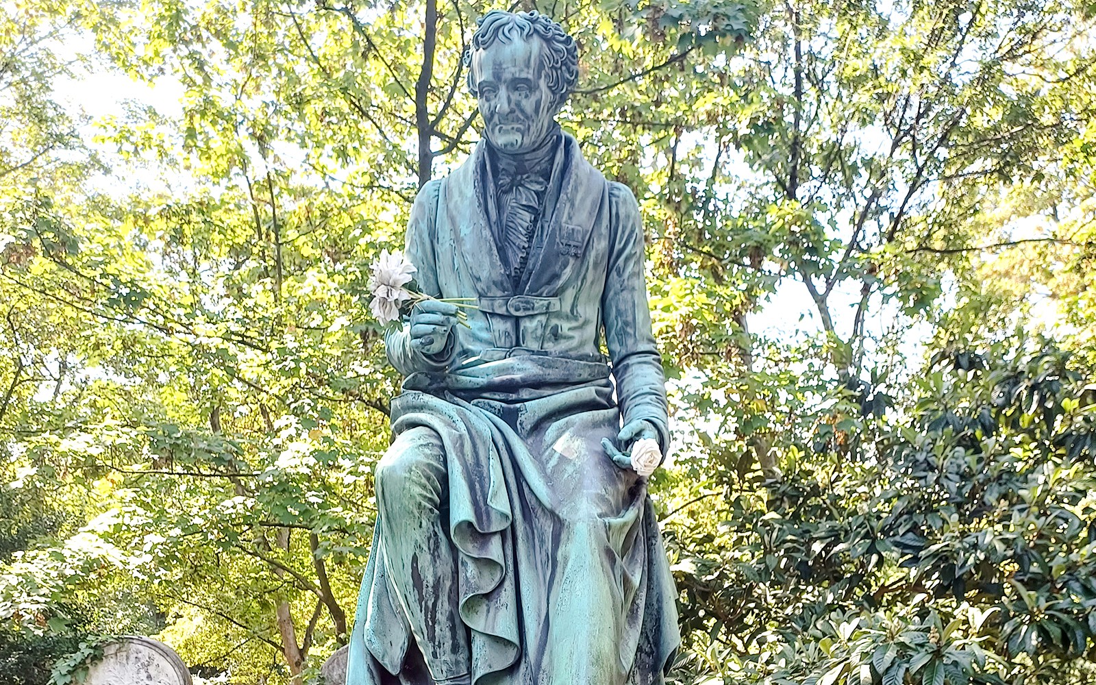 法国巴黎拉雪兹神父公墓中的雕像，周围环绕着树木和墓碑。